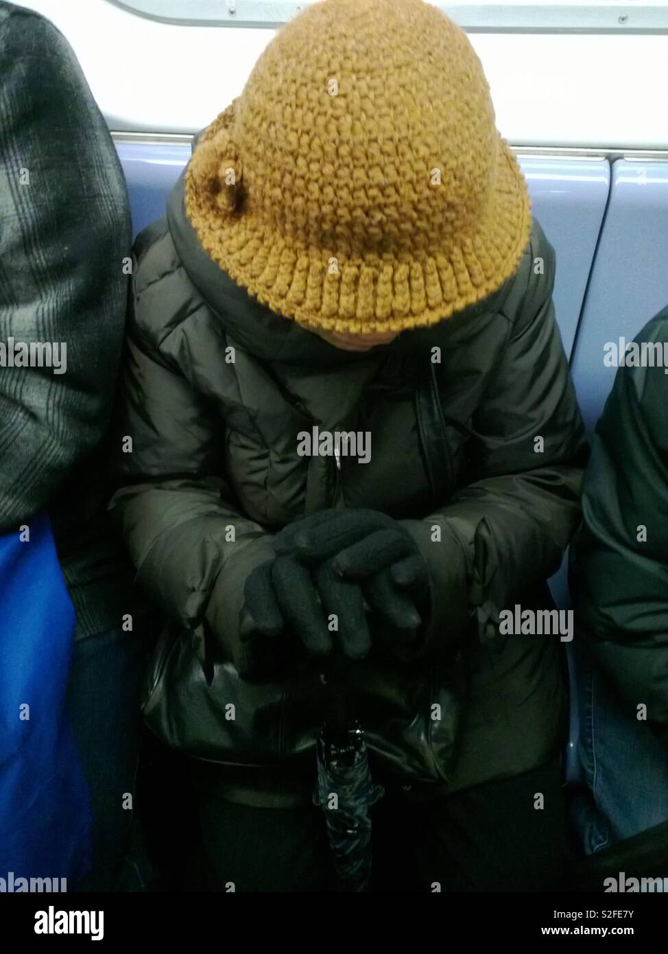 Old lady dressed for winter in NYC wearing a yellow hat, in the Subway - Smartphone Captured Stock Image