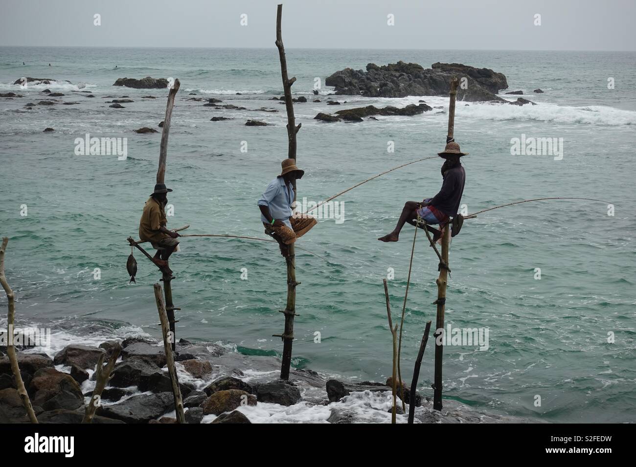 Three stilt fishermen in sri lanka Stock Photo