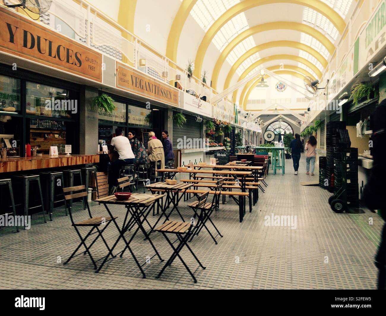 Indoor food market with customers seated at bar stools at a restaurant in Arenal Seville Spain - Smartphone Captured Stock Image