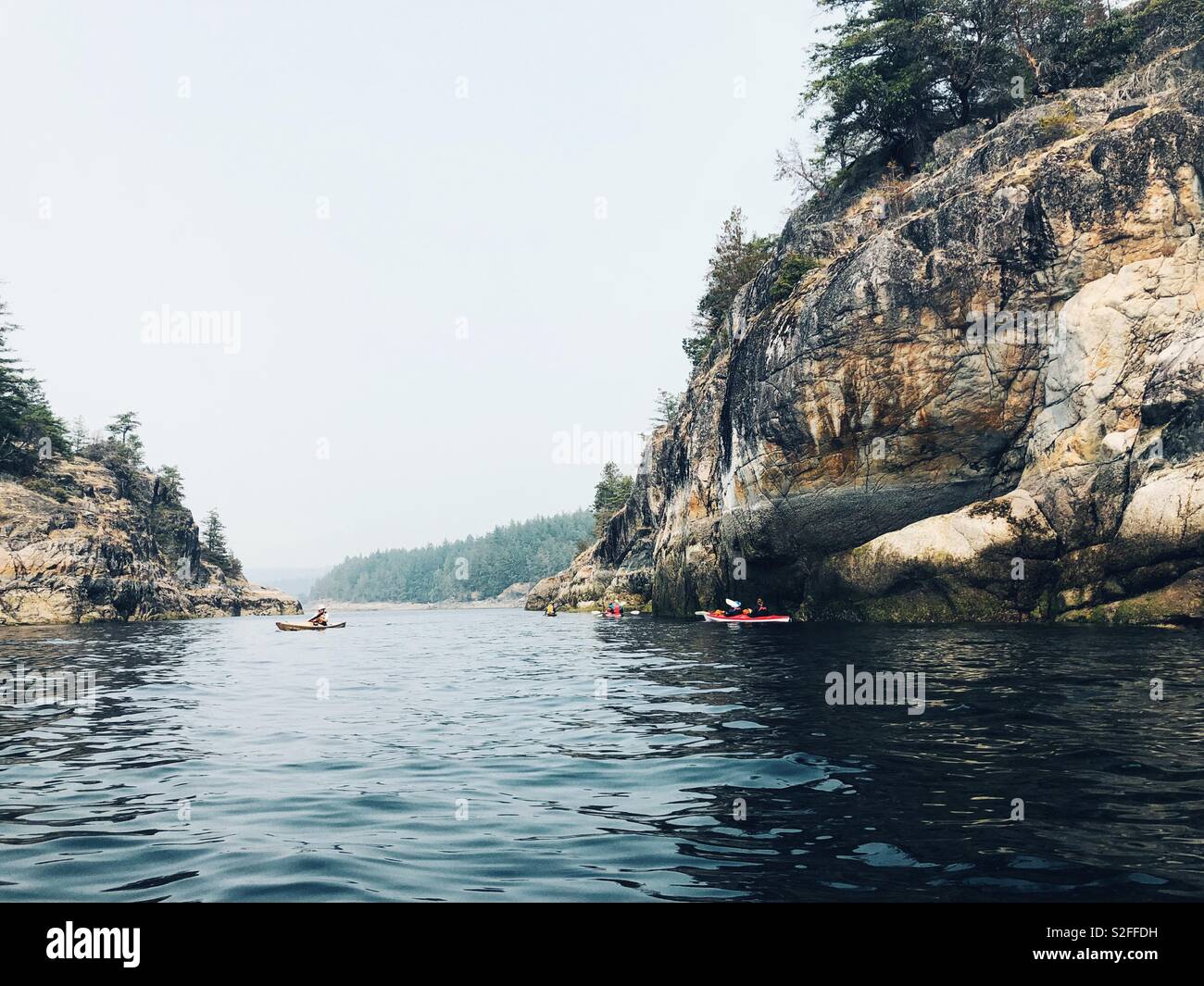 Kayakers explore bluffs of Copeland Islands in search for marine life in British Columbia Stock Photo