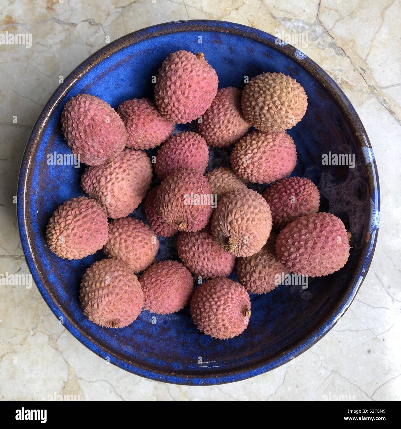Lychees in a blue ceramic bowl on marble Stock Photo