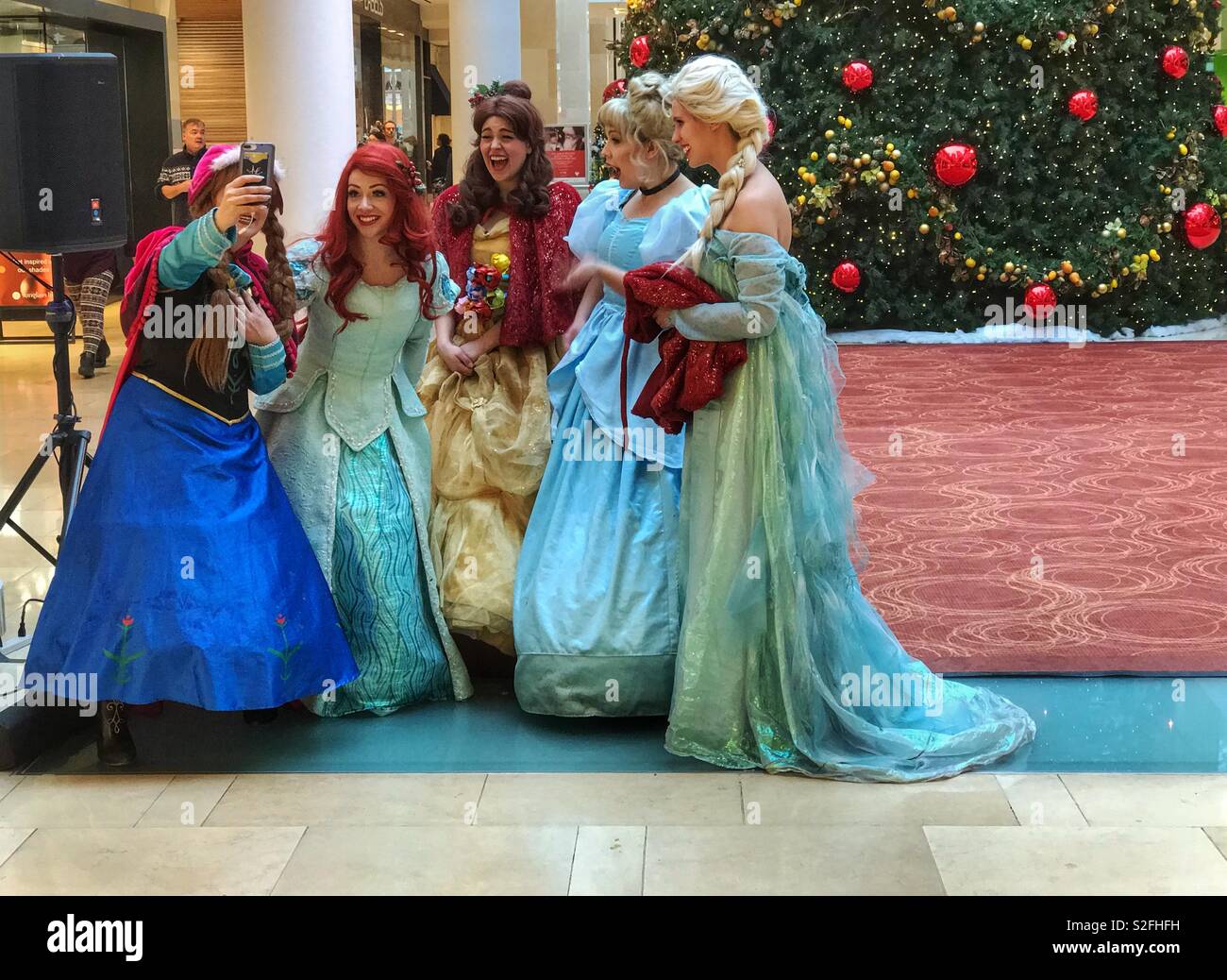 Princesses taking a selfie in front of a giant Christmas tree. Taken in downtown Calgary, Alberta, Canada. Stock Photo