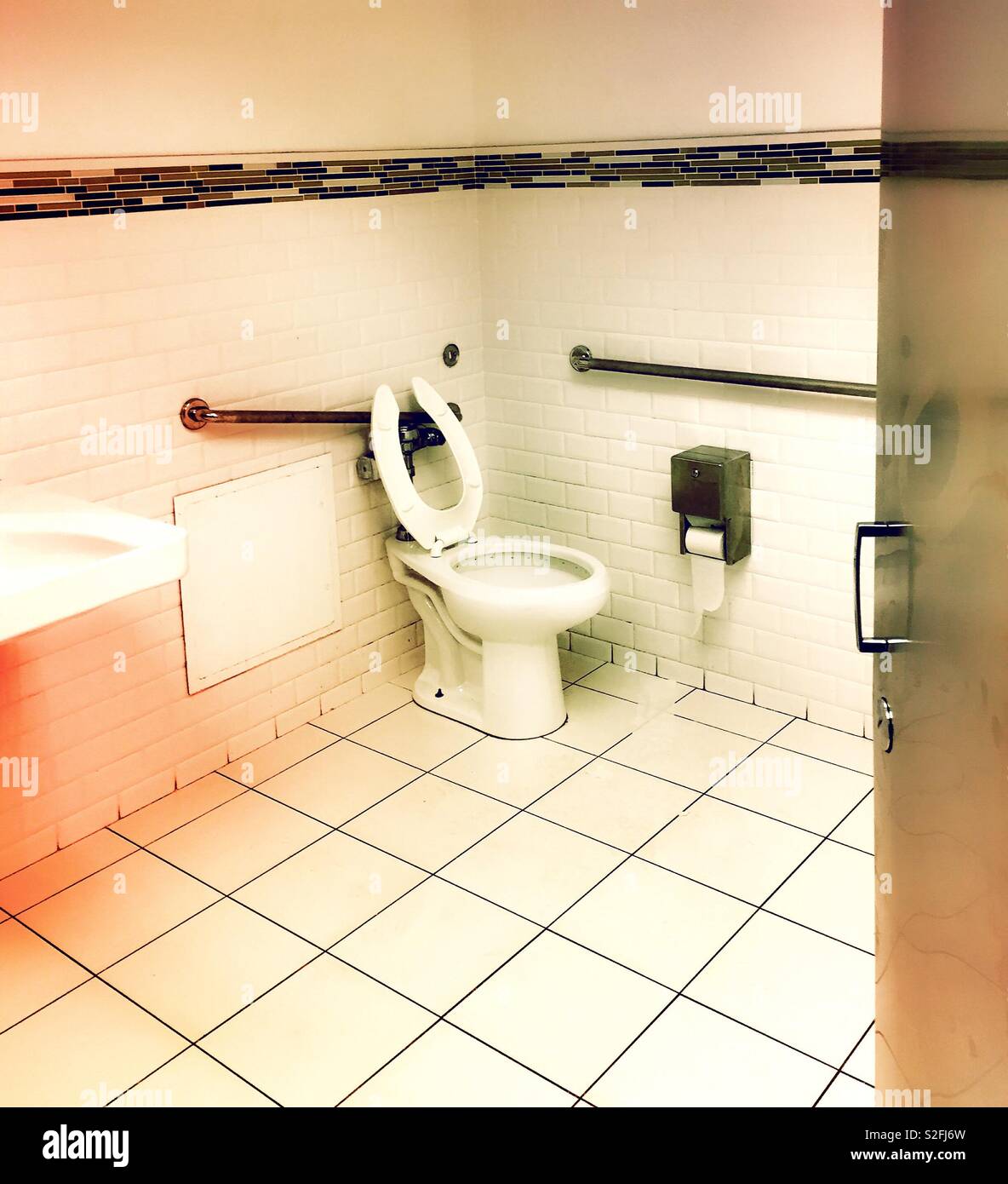 A white public restroom with disability access bars and toilet sizing, USA - Smartphone Captured Stock Image