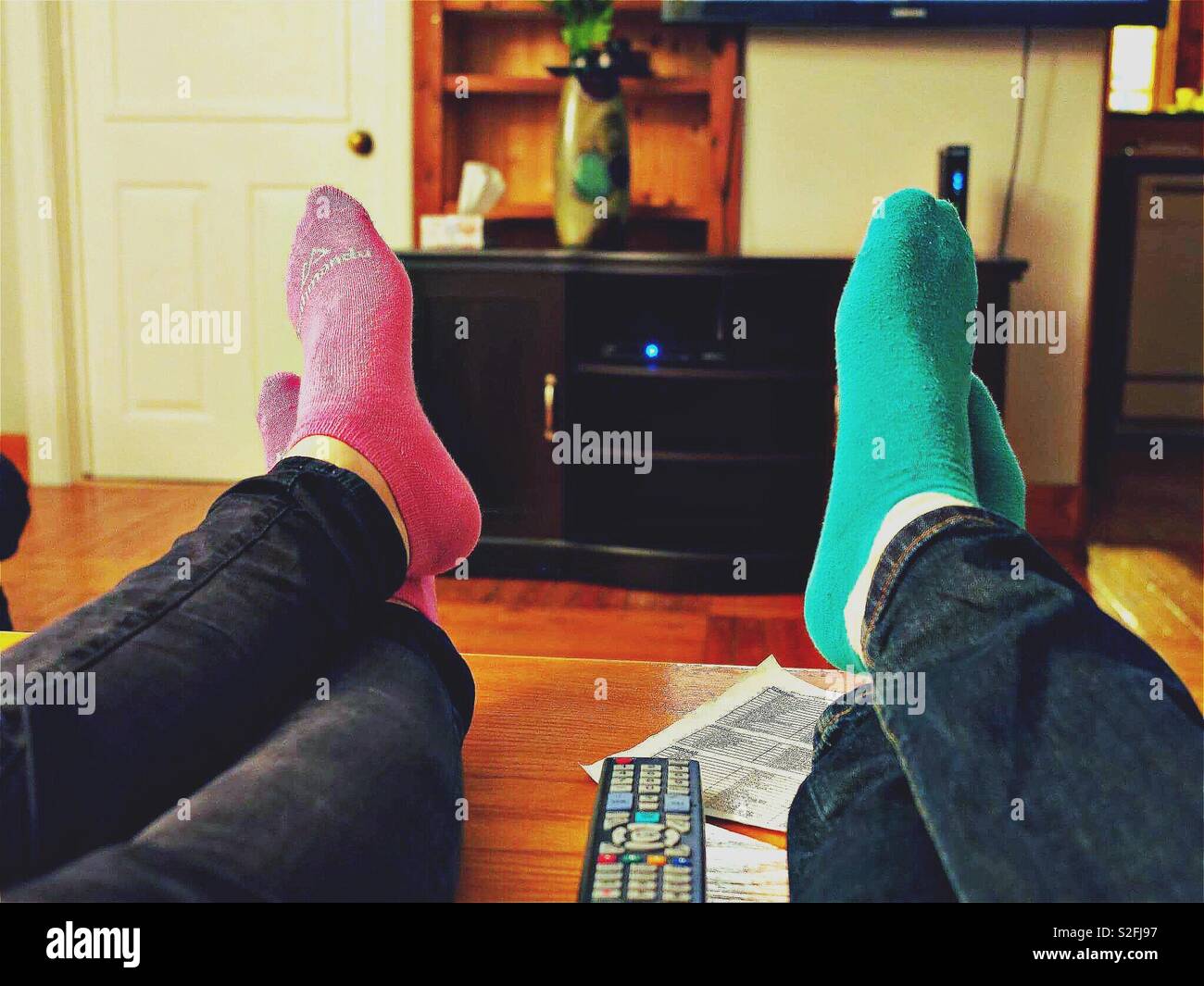 Couples putting their feet up relaxing in lounge room - Smartphone Captured Stock Image