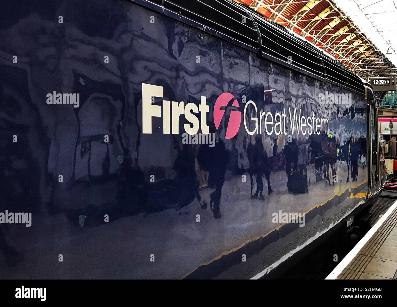Passengers walking along a platform reflected in the shiny paintwork of a First Great Western diesel locomotive Stock Photo