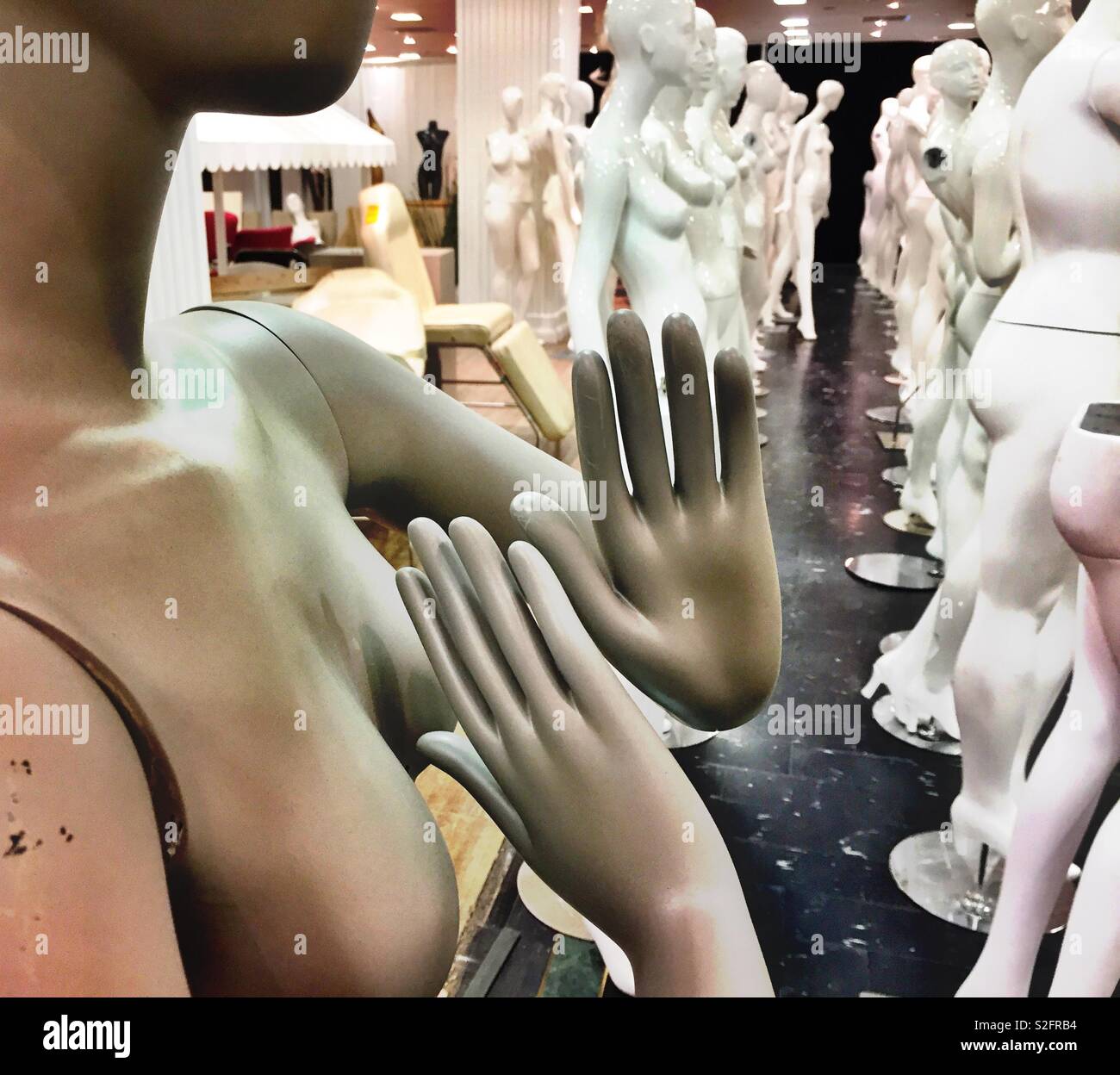 Female manikin with her hands raised in front of rows of manikins - Smartphone Captured Stock Image