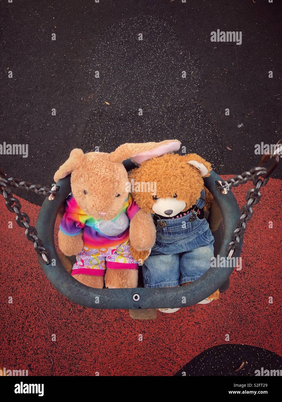 2 build-a-bear teddies in a baby swing in a park Stock Photo