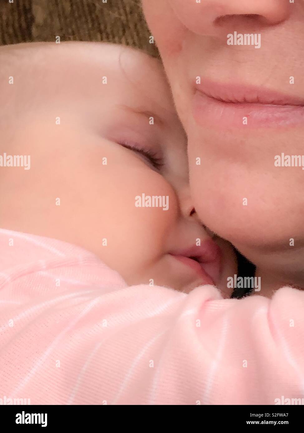A close up of a baby girl sleeping next to a woman’s chin. Stock Photo
