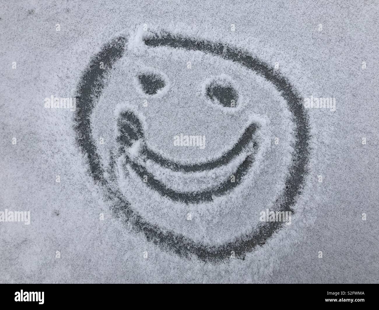 Happy smiling face on a snow covered car Stock Photo