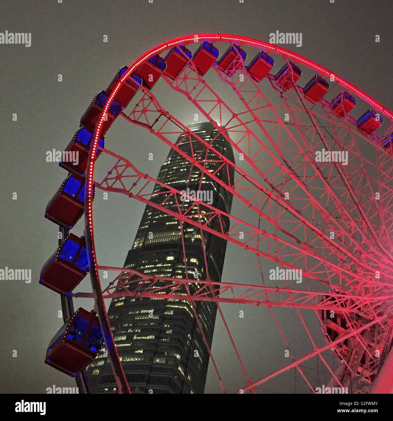 The Hong Kong Observation Wheel at the Central waterfront at night, with 2ifc, Hong Kong Island's tallest skyscraper - Smartphone Captured Stock Image