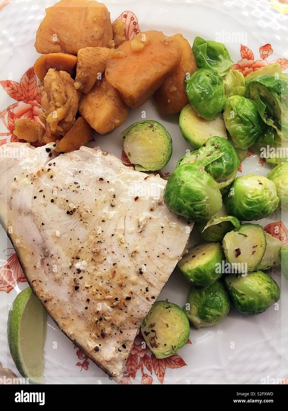 Gourmet meal of broiled swordfish steak, brussels sprouts and sweet potatoes on fine China. - Smartphone Captured Stock Image