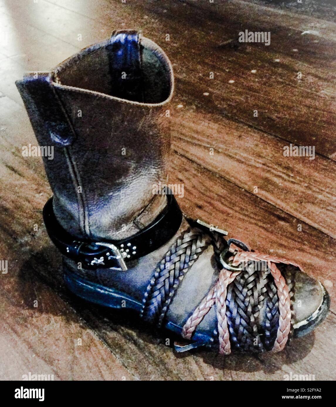 Well exposed photo of leather cowboy boot wrapped in leather belts used as clamps after glue was applied for repairs - Smartphone Captured Stock Image