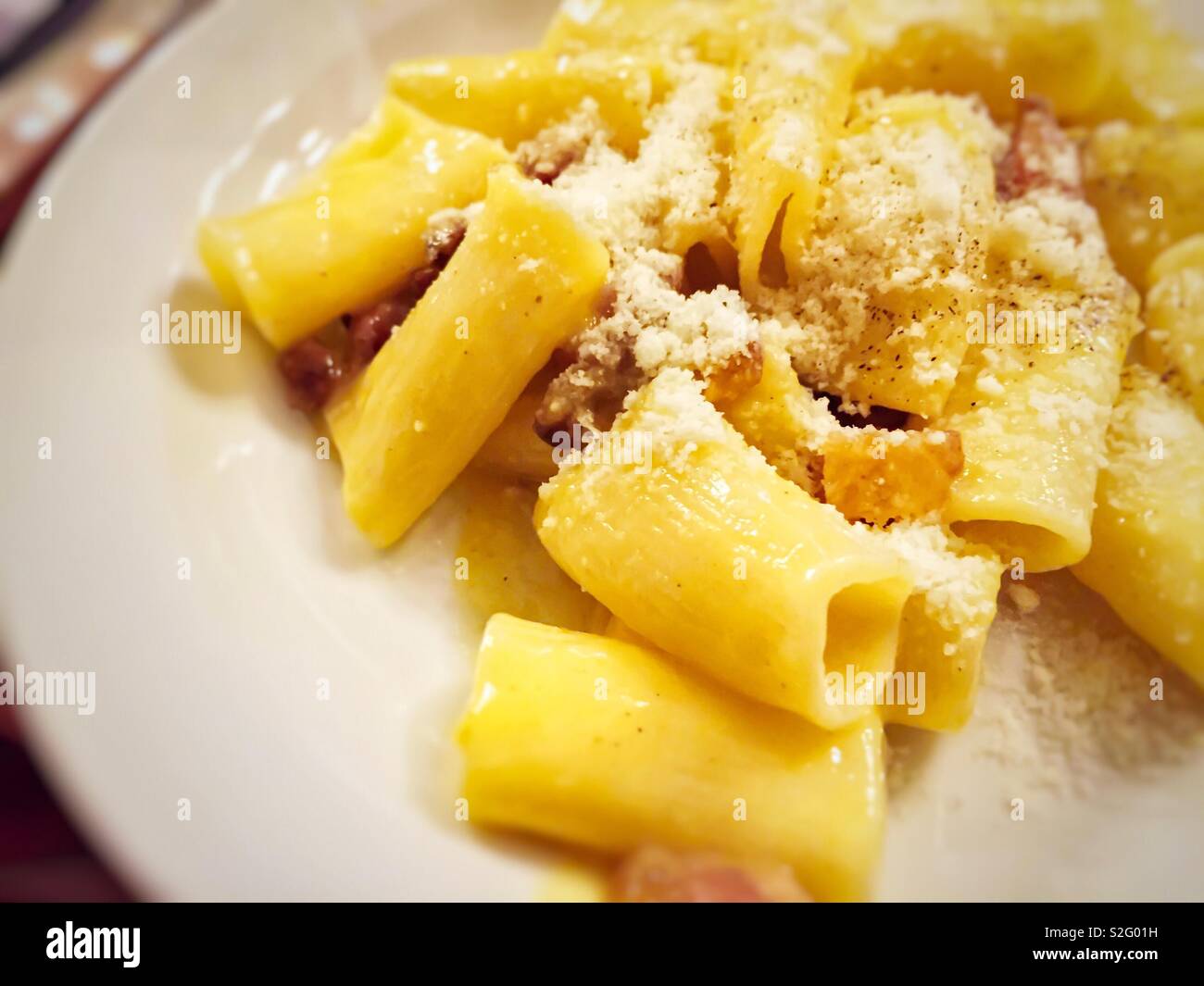 close-up view of a plate of macaroni pasta with carbonara sauce prepared with eggs, bacon, pepper and grated parmesan - Smartphone Captured Stock Image