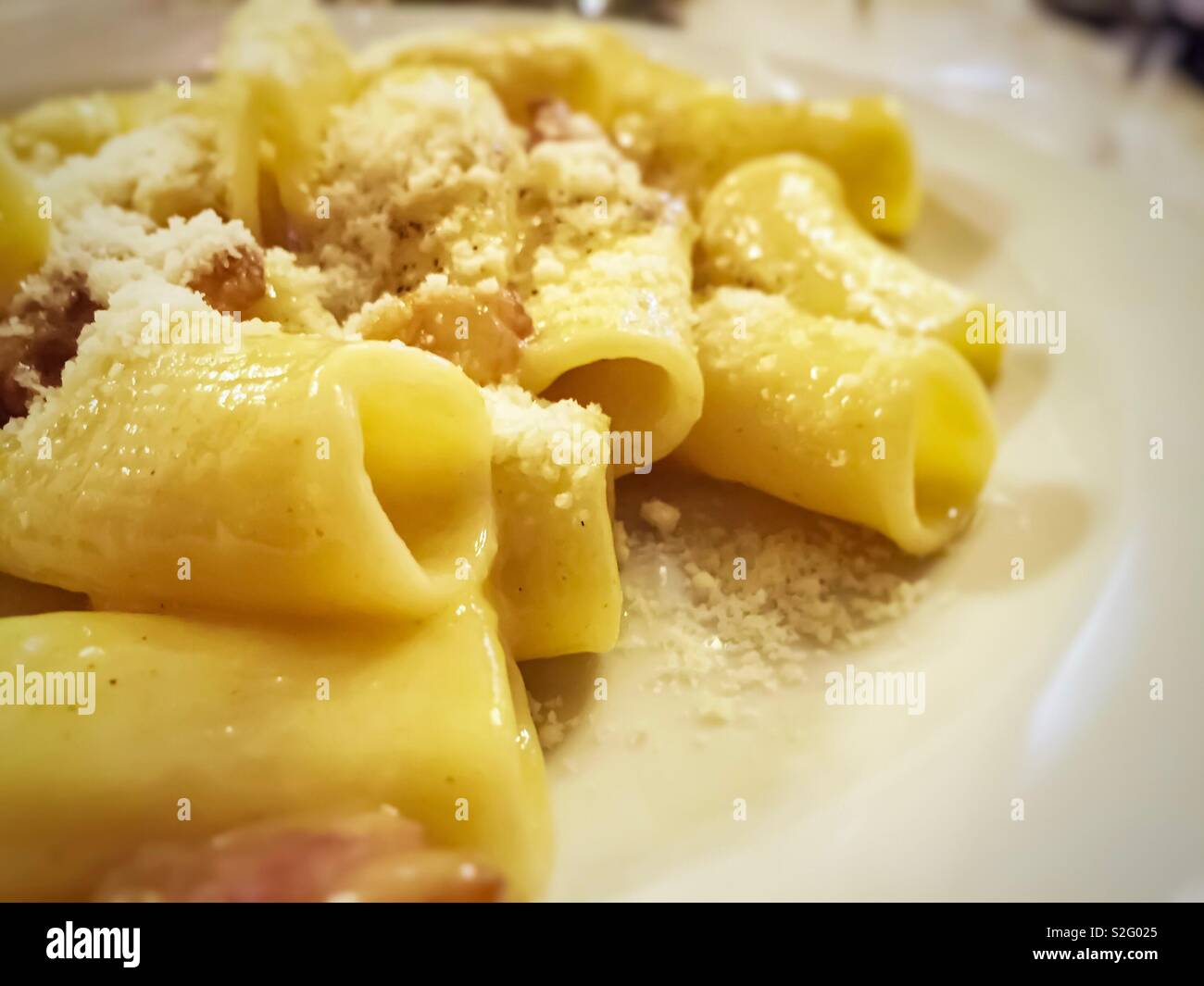 close-up view of a plate of macaroni pasta with carbonara sauce prepared with eggs, bacon, pepper and grated parmesan - Smartphone Captured Stock Image