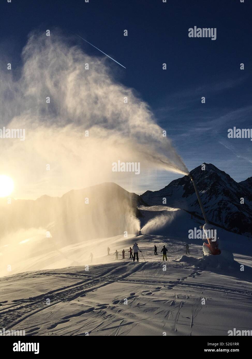 The Sun shining through snow canon spray on a ski slope in the morning. Stock Photo