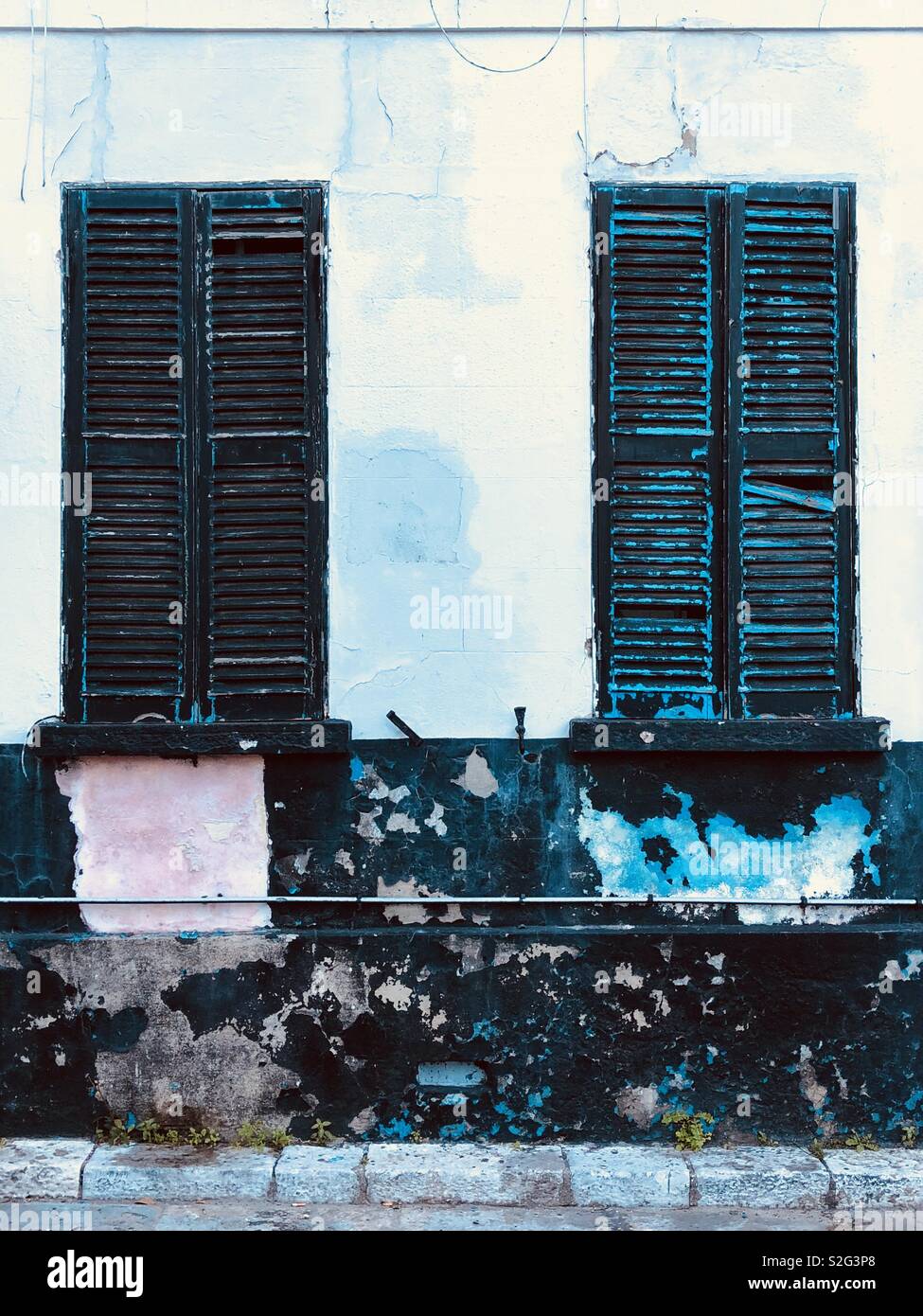 Two windows with black shutters and lots of cracked peeling paint - Smartphone Captured Stock Image