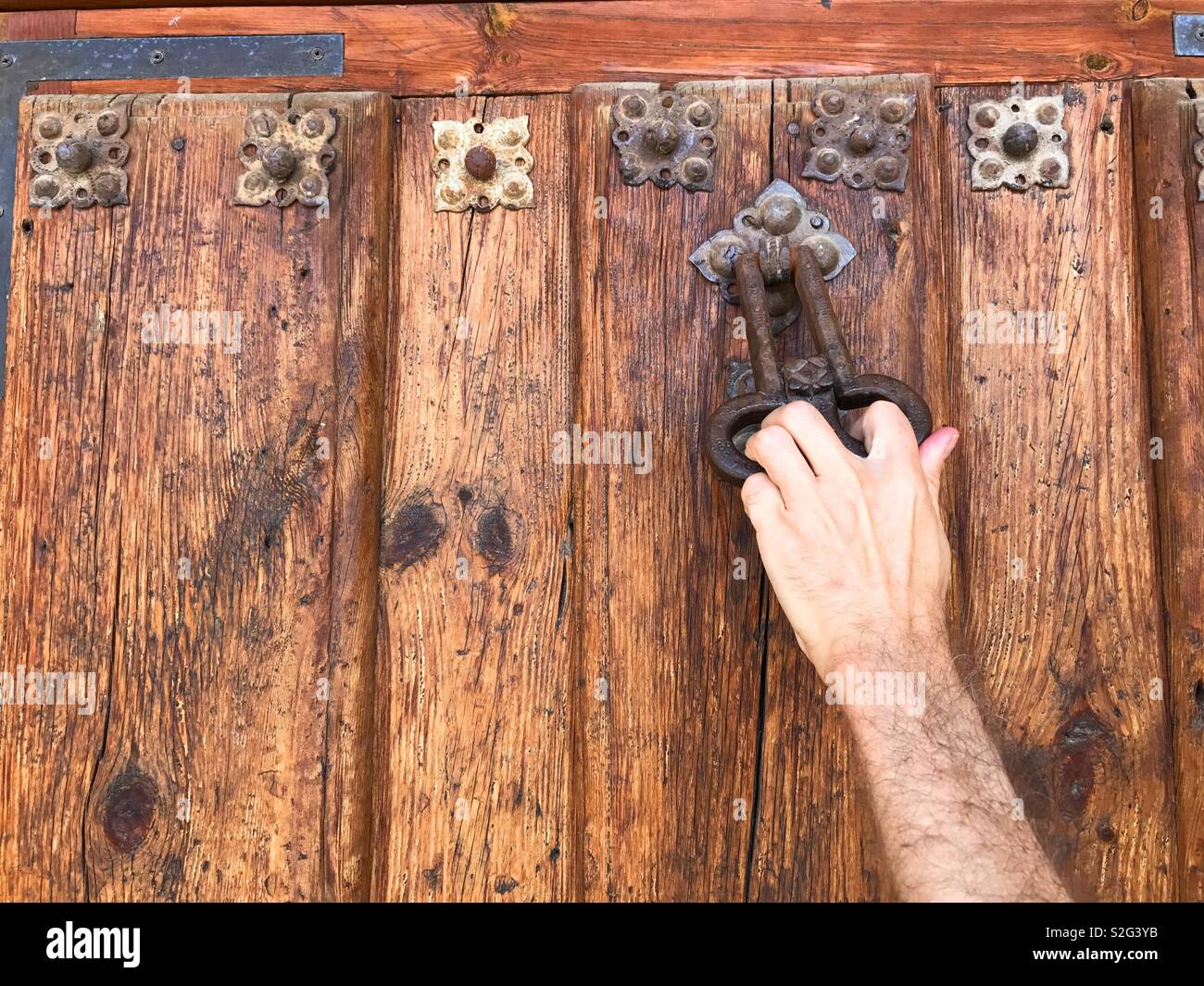 Man's hand knocking at wooden door. Stock Photo