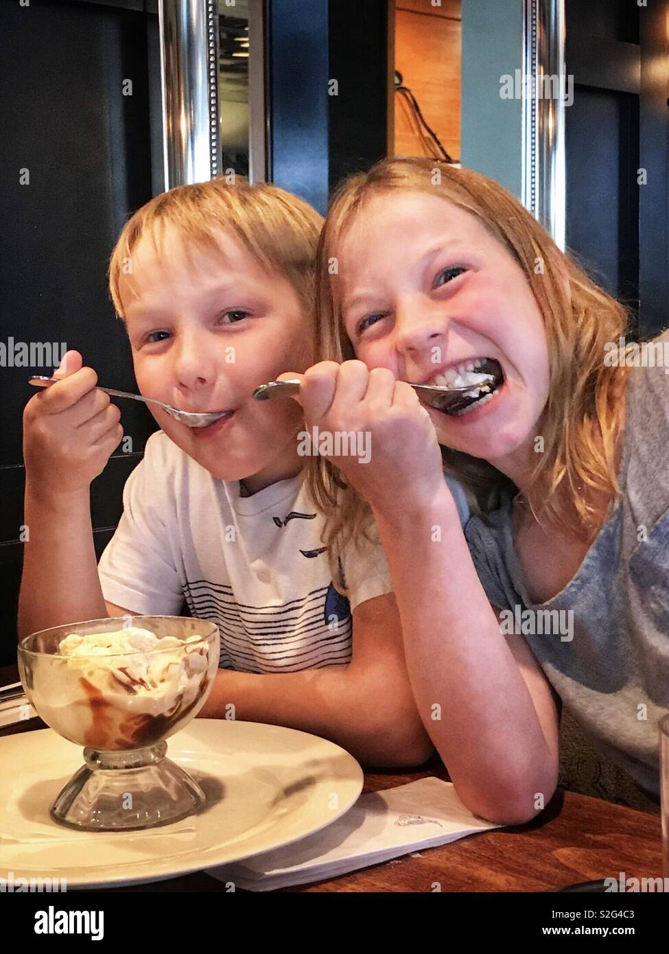 A boy and girl share an ice cream dessert. Stock Photo
