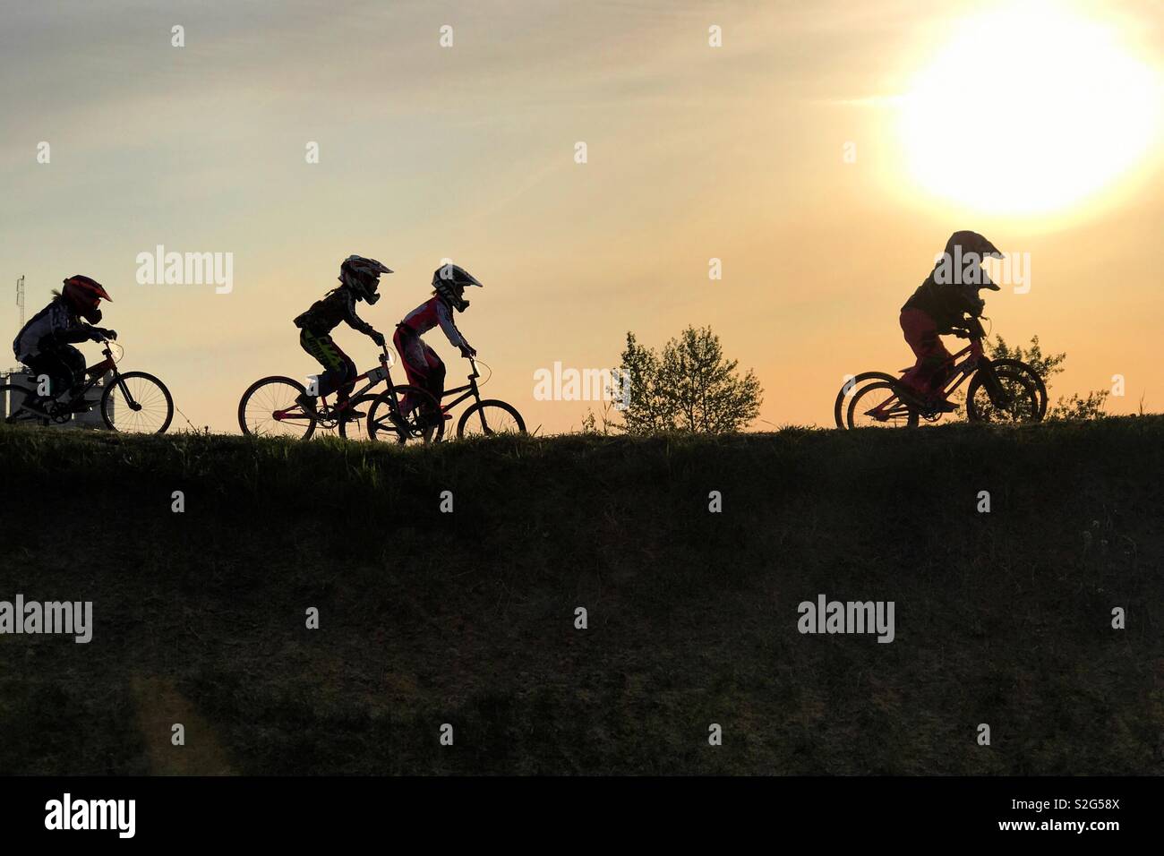 Young BMX racers silhouetted during a race. Stock Photo