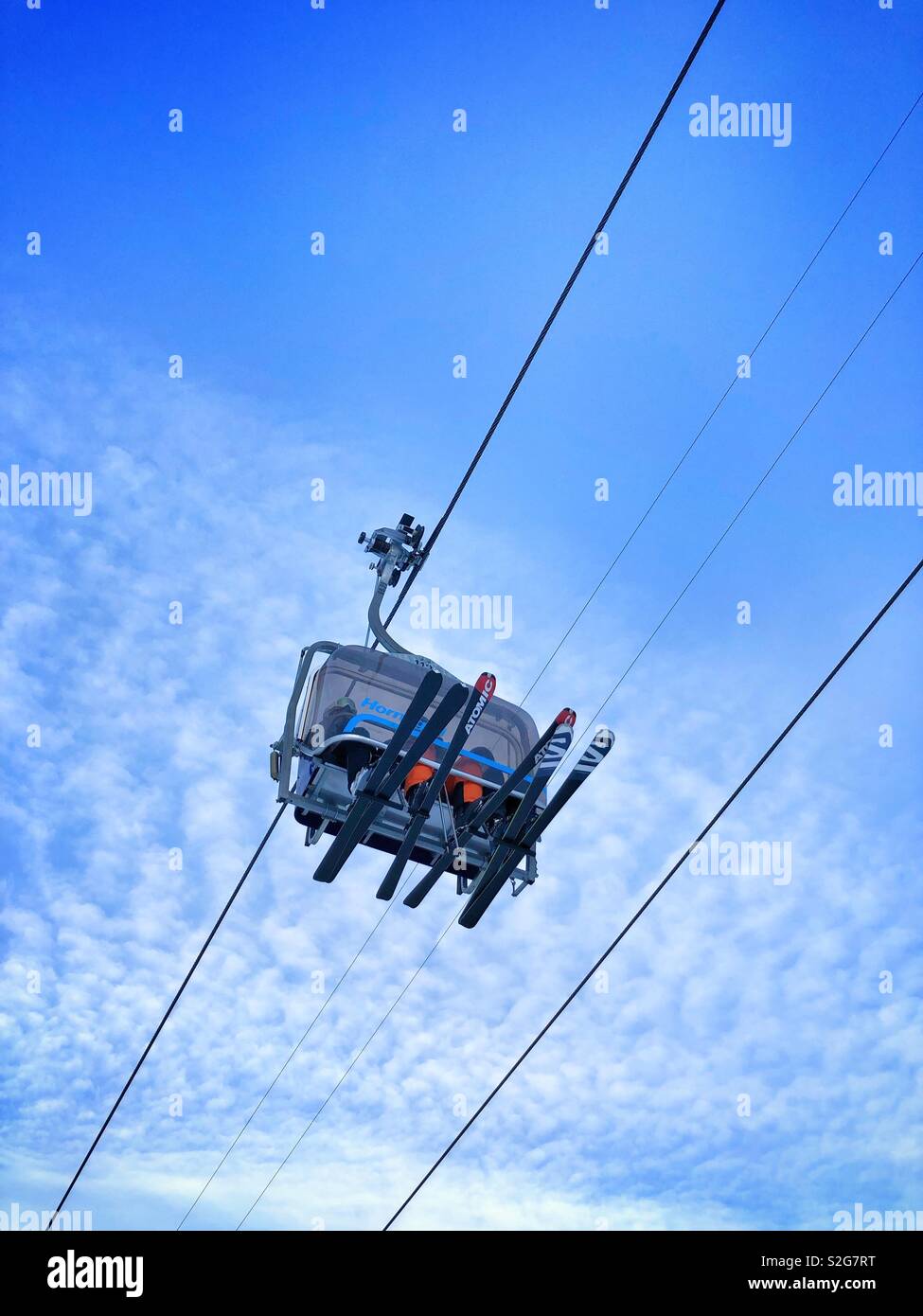 Ski lift with skiers in blue sky - Smartphone Captured Stock Image