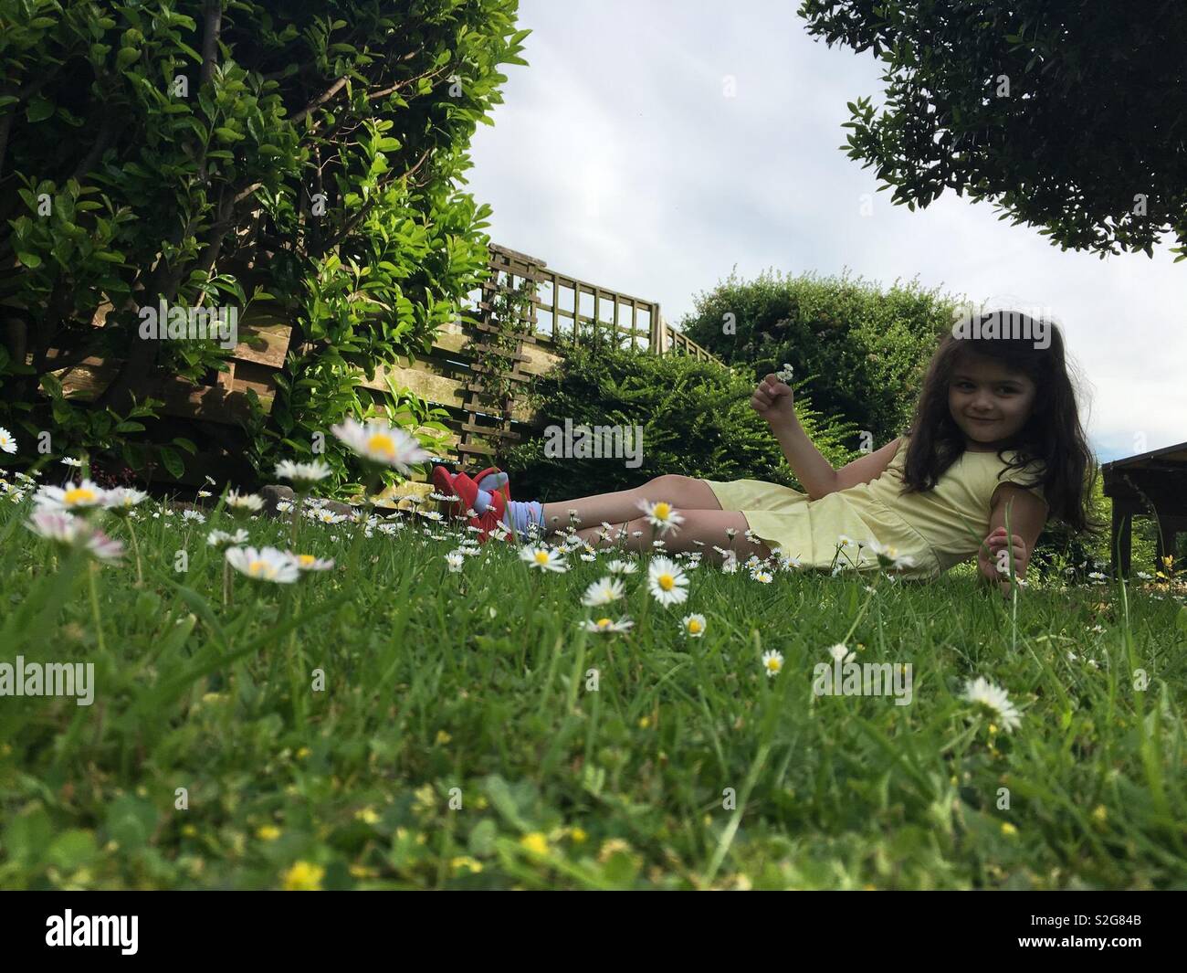 Girl sitting in garden of Daisy’s Stock Photo