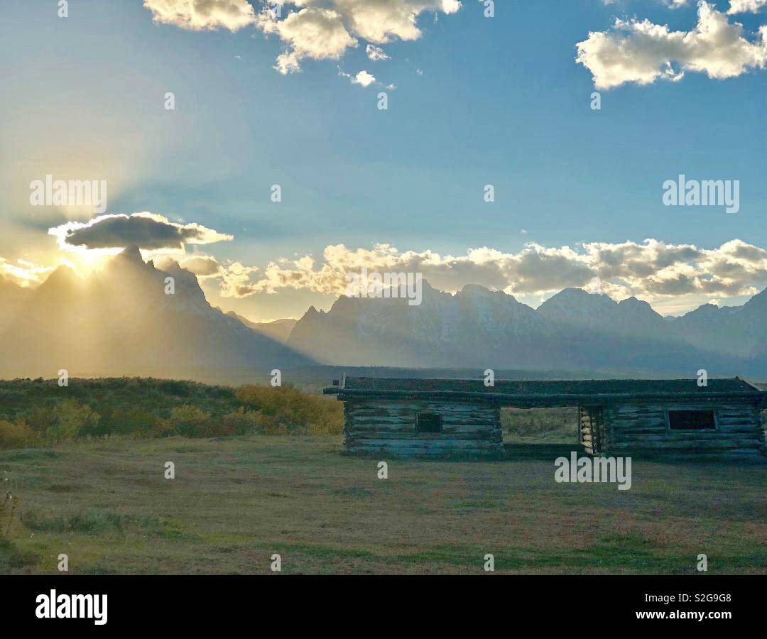 Sunlight burst over a valley in western Wyoming with the grand Teton mountains in the background. Cunningham cabin. Stock Photo