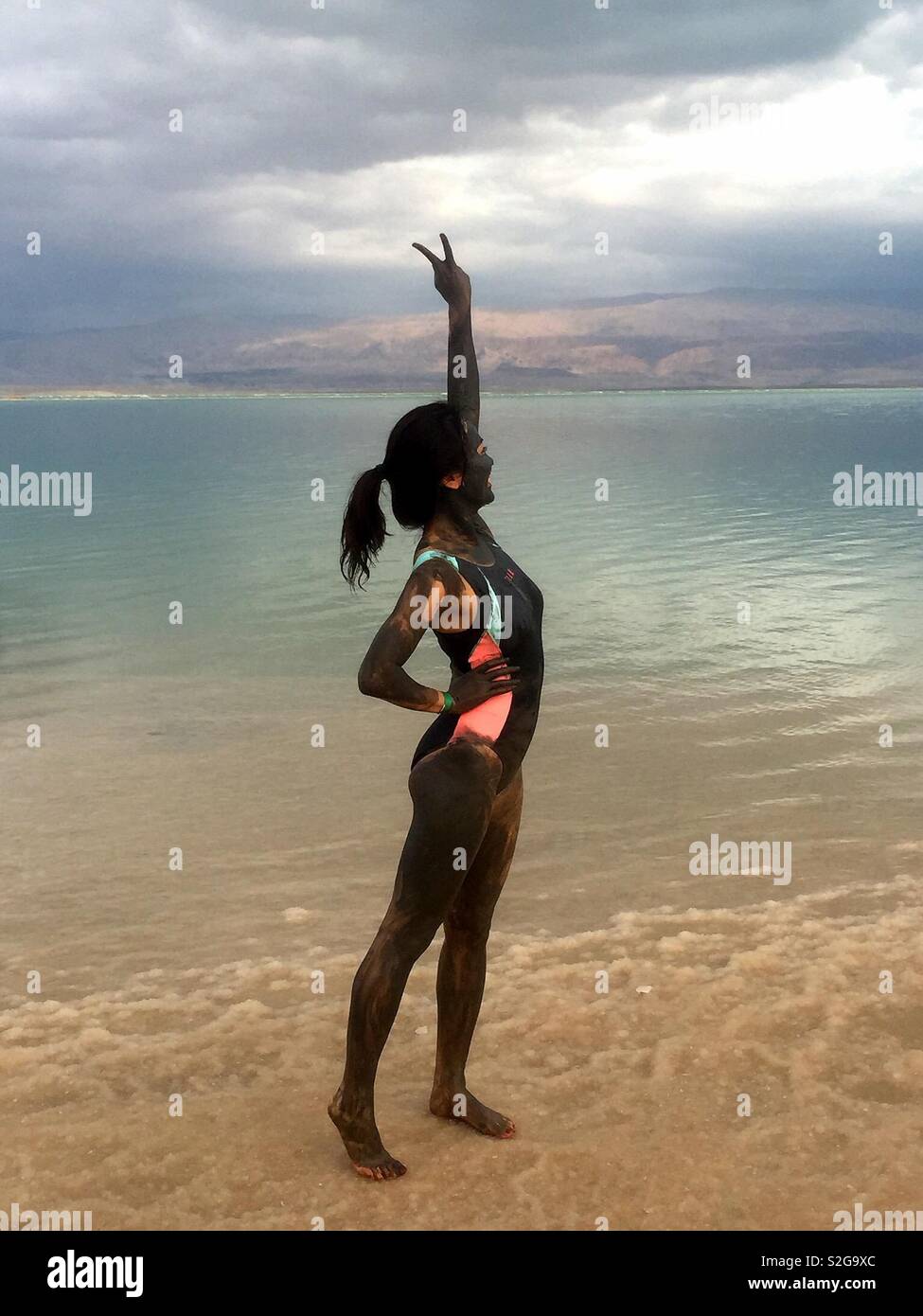 A tourist covered with Dead Sea mud on the Dead Sea beach in Israel. - Smartphone Captured Stock Image