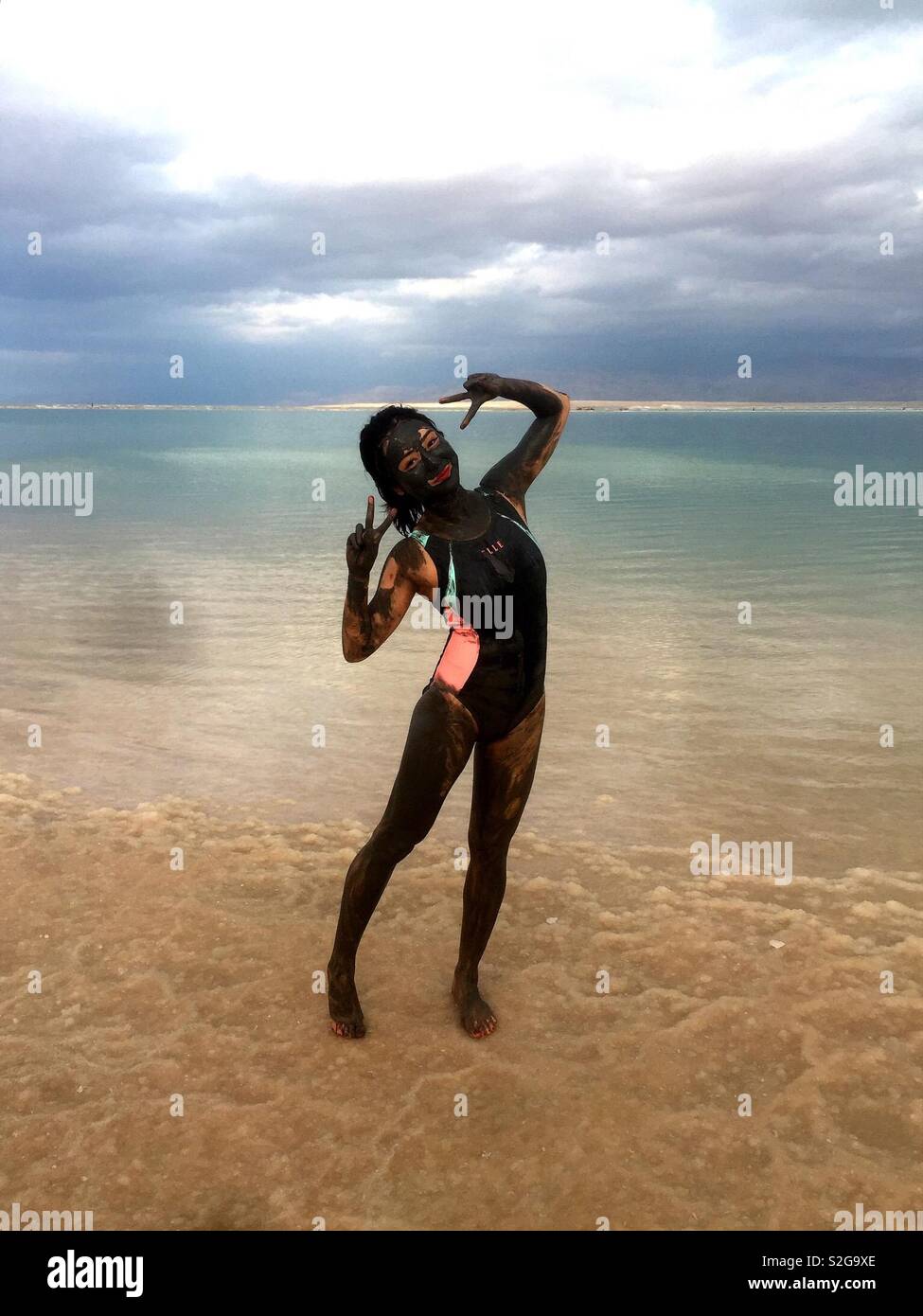 A tourist covered with Dead Sea mud on the Dead Sea beach in Israel. - Smartphone Captured Stock Image
