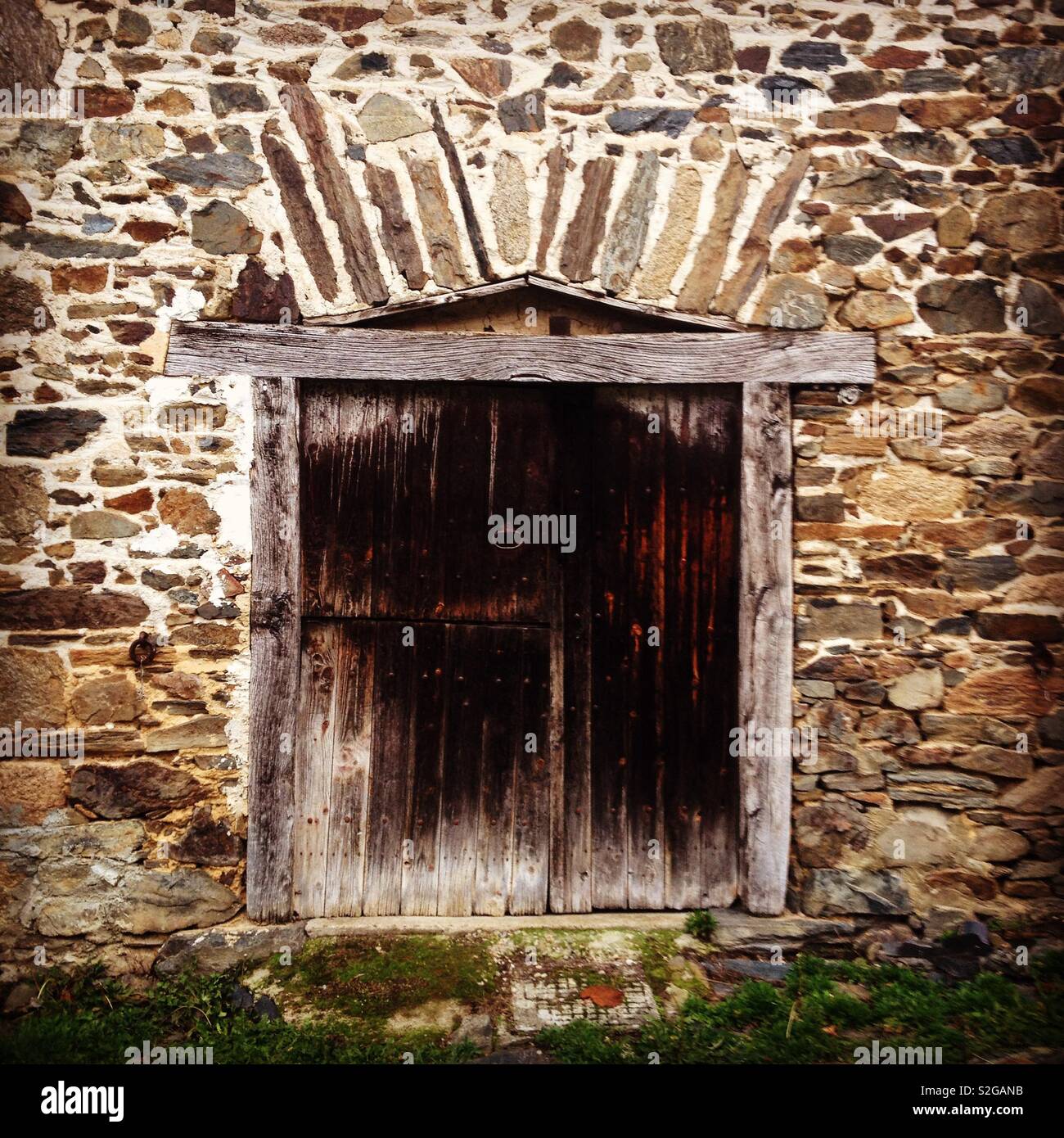 An old wooden door on a stone wall - Smartphone Captured Stock Image