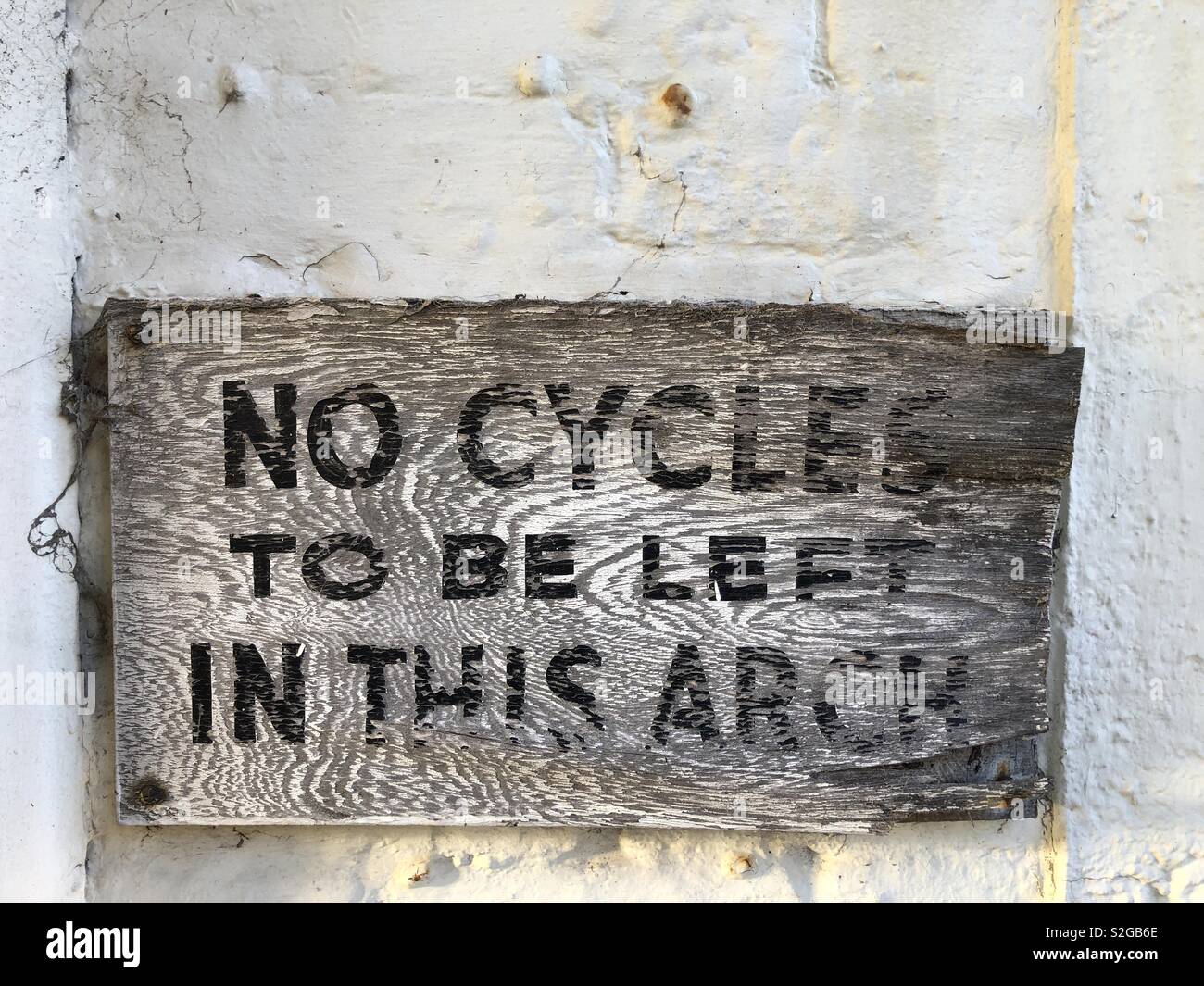 Bleached wooden sign warning that bicycles should not be left in this location - Smartphone Captured Stock Image