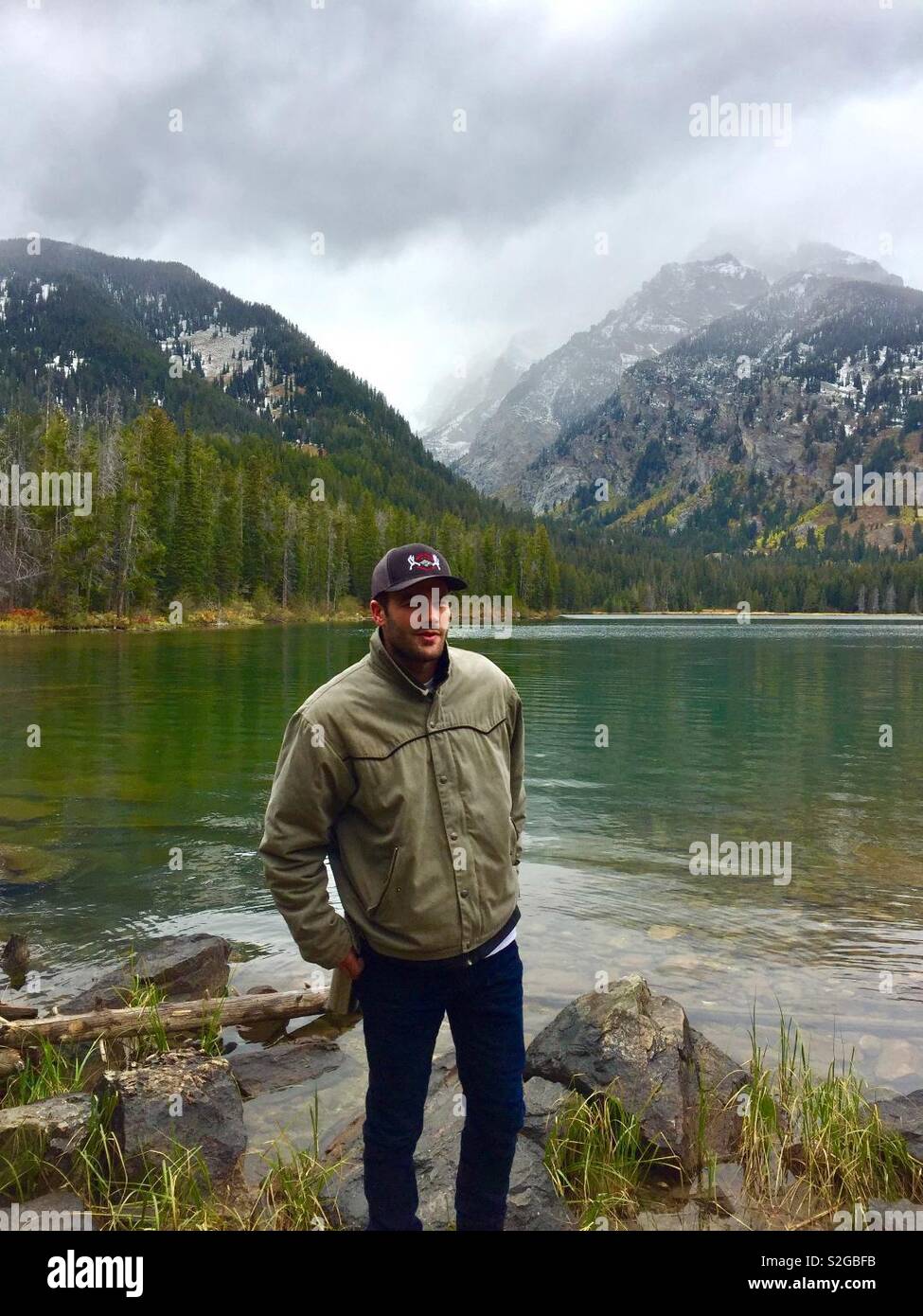 Young man standing in front of Tygart lake in the grand Tetons, Wyoming. Accessible only by Hiking or horseback. - Smartphone Captured Stock Image