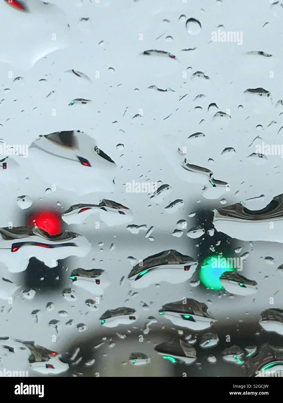 Red and green traffic lights viewed through a wet glass. - Smartphone Captured Stock Image