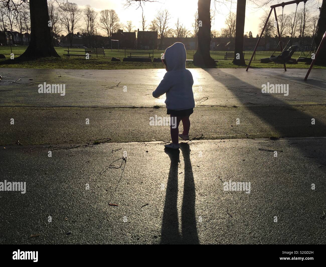Baby in a park silhouette against strong sun. Playground Stock Photo