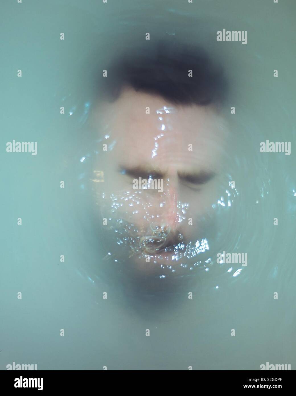 Guy with beard and eyes closed is submerged under milky colored water. - Smartphone Captured Stock Image
