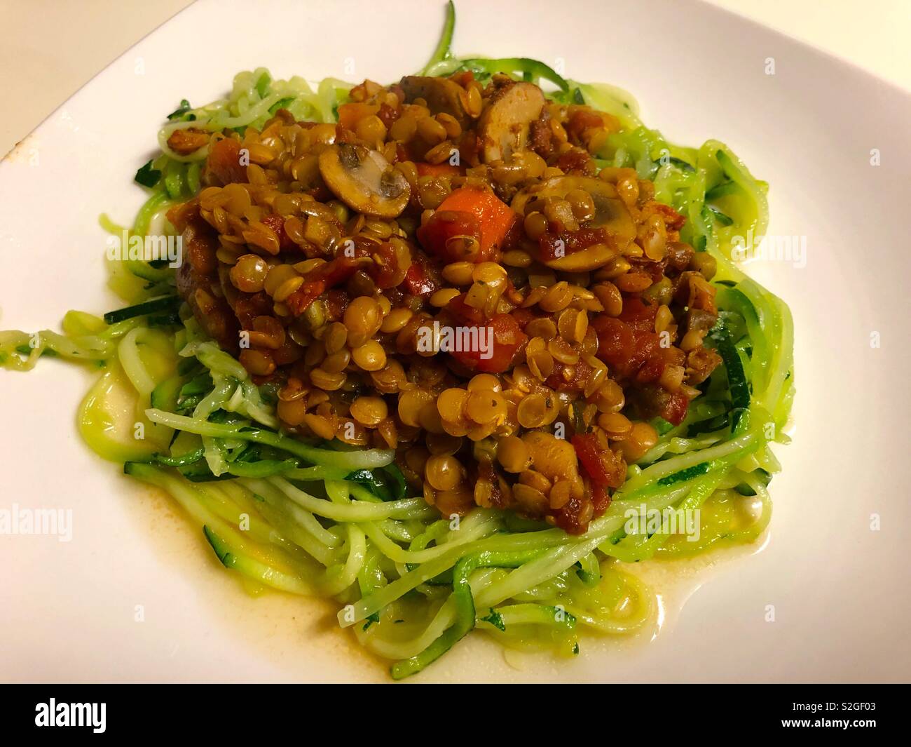 A healthy meal of vegetables and lentils in a tomato sauce over a bed of shredded zucchini ( couchette.) Stock Photo