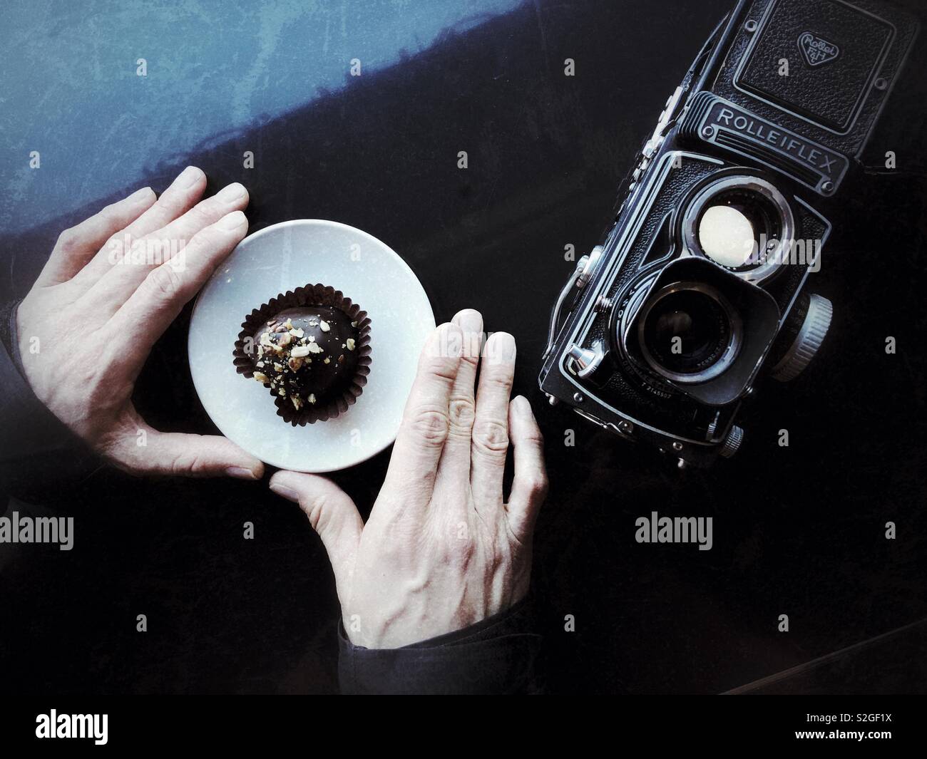 Man’s hands holding plate with chocolate treat on the table with film camera - Smartphone Captured Stock Image