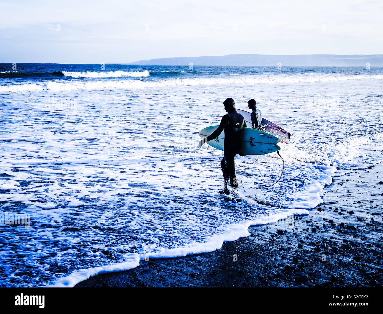 Two surfers walk into the North Sea in winter - Smartphone Captured Stock Image