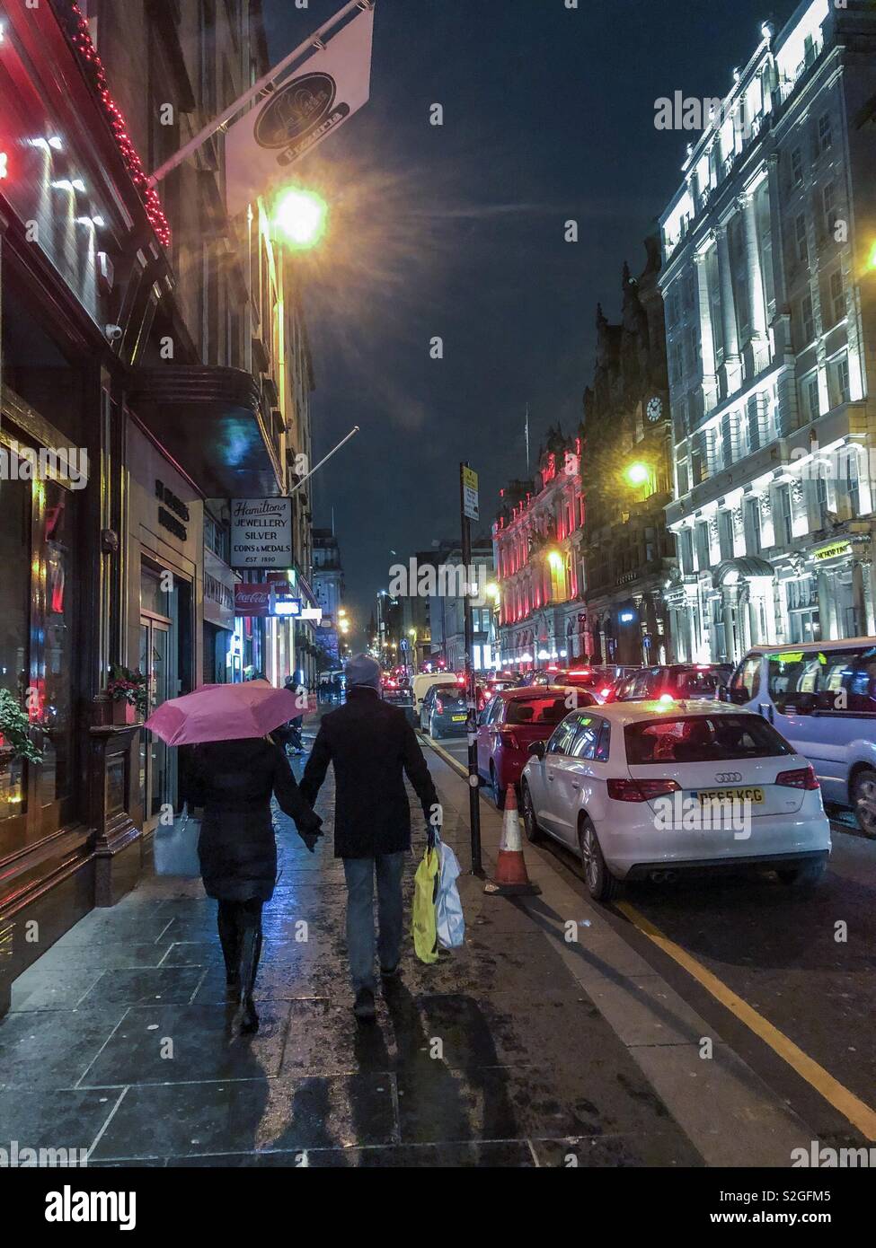 Night scene. Couple walking in St Vincent St. Glasgow city centre. Scotland. UK. - Smartphone Captured Stock Image