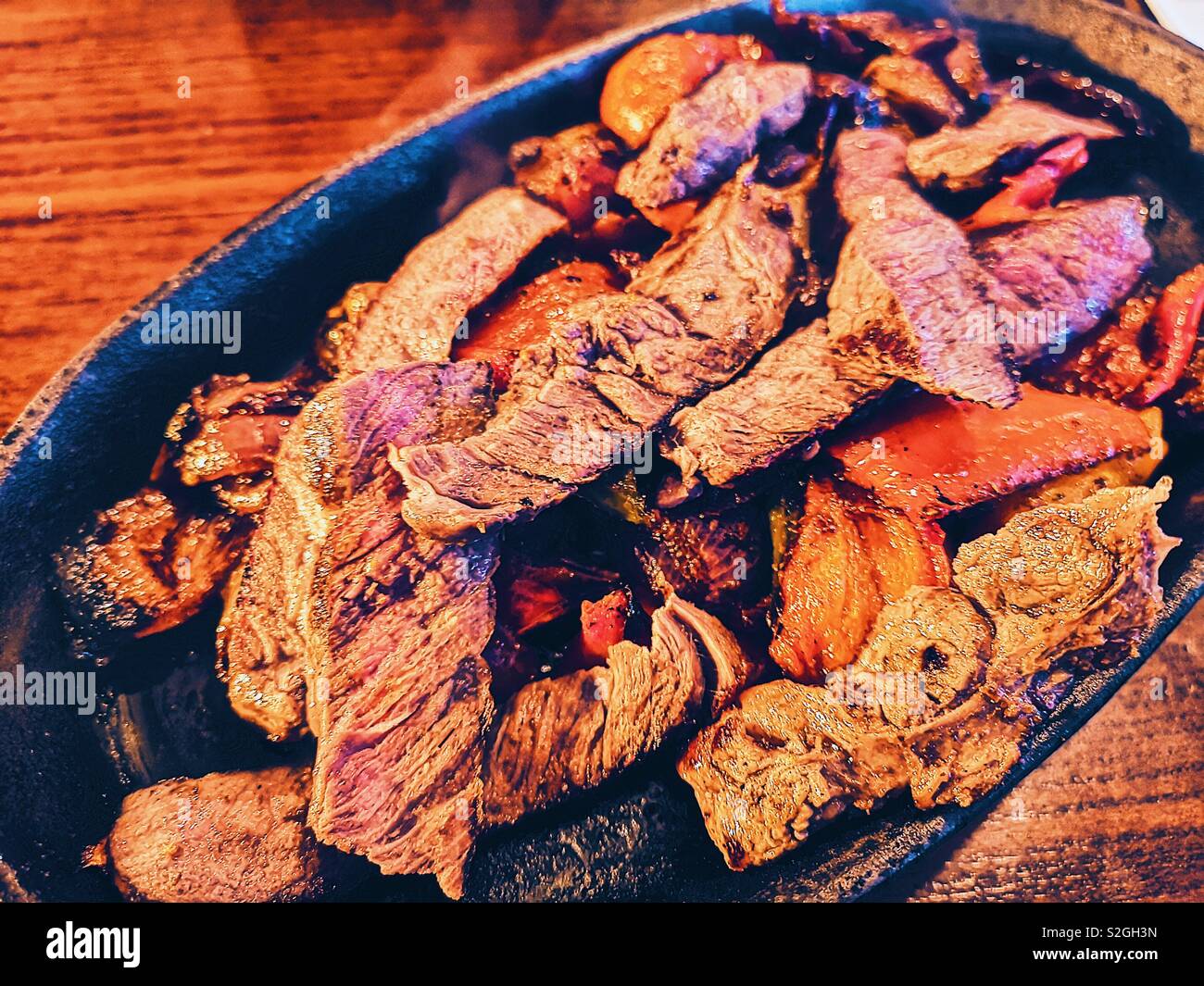 Hot sizzling dish of beef fajitas with peppers and onions - Smartphone Captured Stock Image