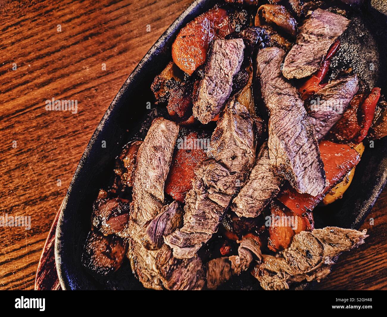 Hot sizzling dish of beef fajitas with peppers and onions - Smartphone Captured Stock Image