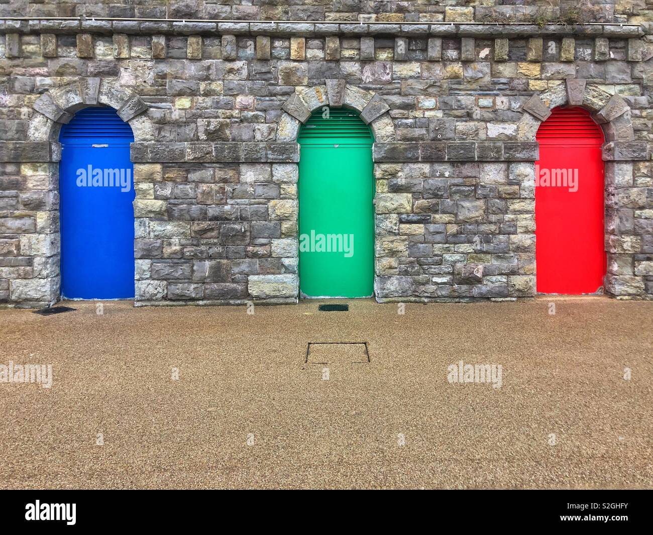 Three coloured doors in a wall at Barry Island, South Wales. Stock Photo