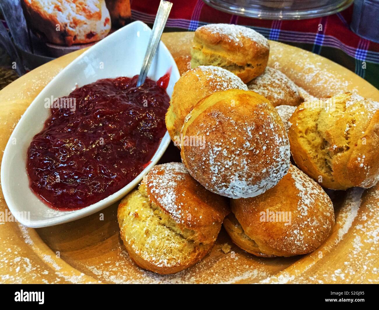 A plate of fresh scones accompanied by a dish of fruit jam. - Smartphone Captured Stock Image