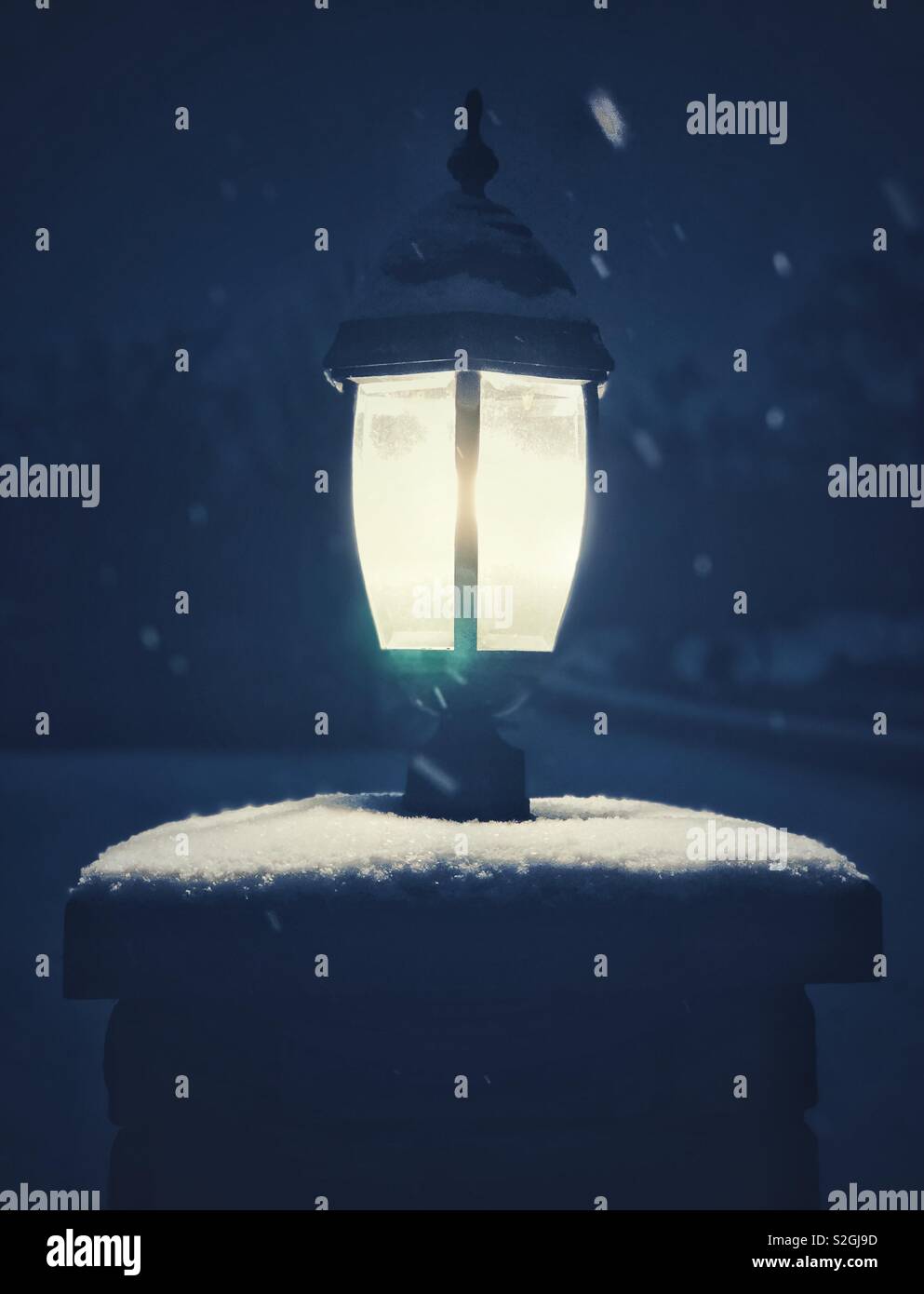 Solitary street lamp on snow covered pillar in the dark with snow falling - Smartphone Captured Stock Image