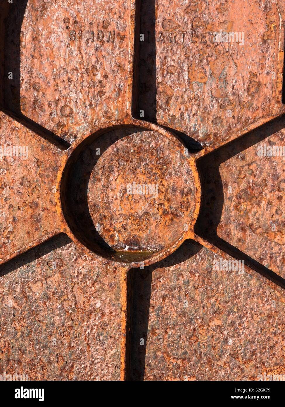 Close up of a geometric, weathered storm drain cover rusted by seawater Stock Photo