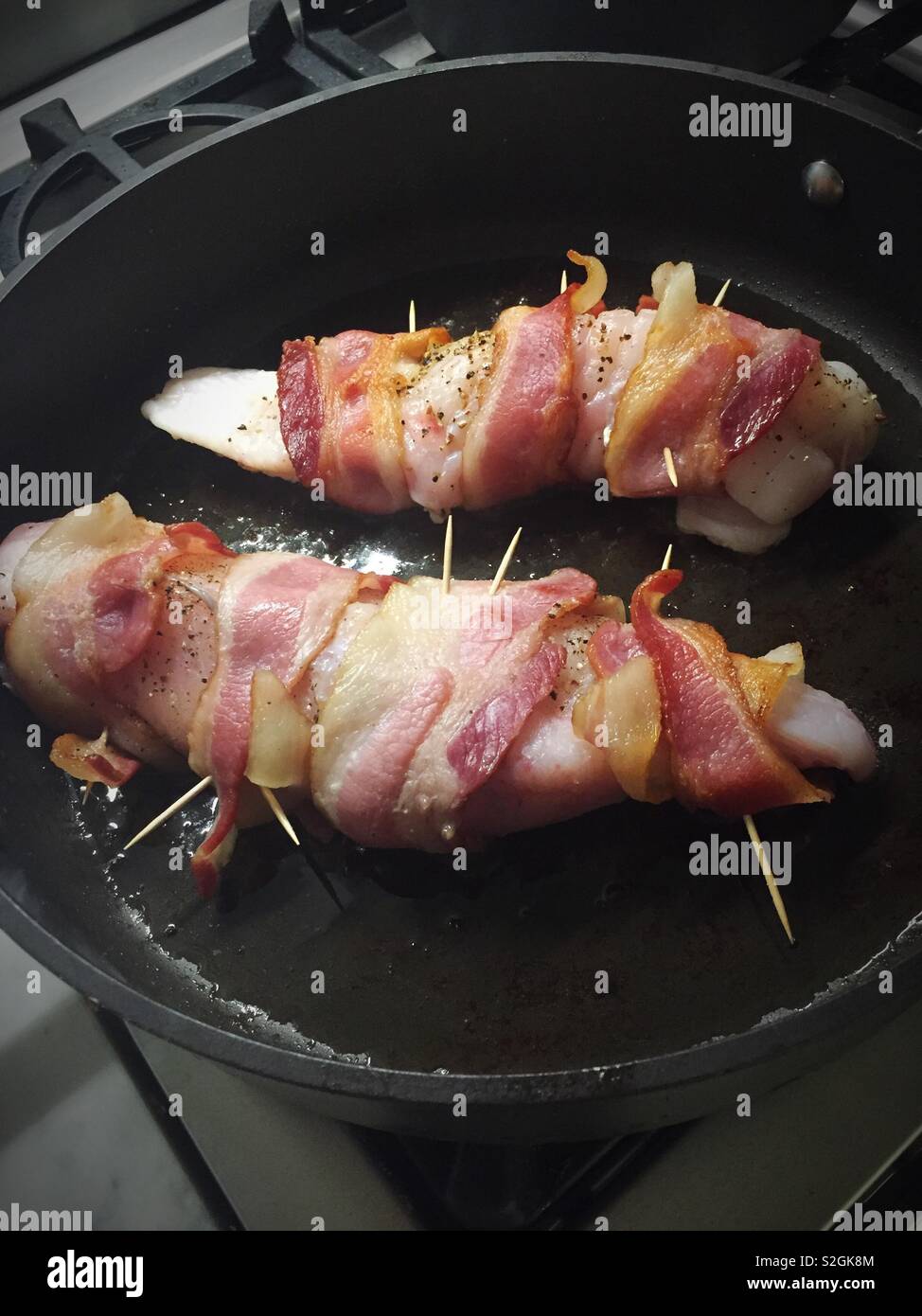 Monk fish fillet wrapped in bacon sautéing in a skillet, USA - Smartphone Captured Stock Image