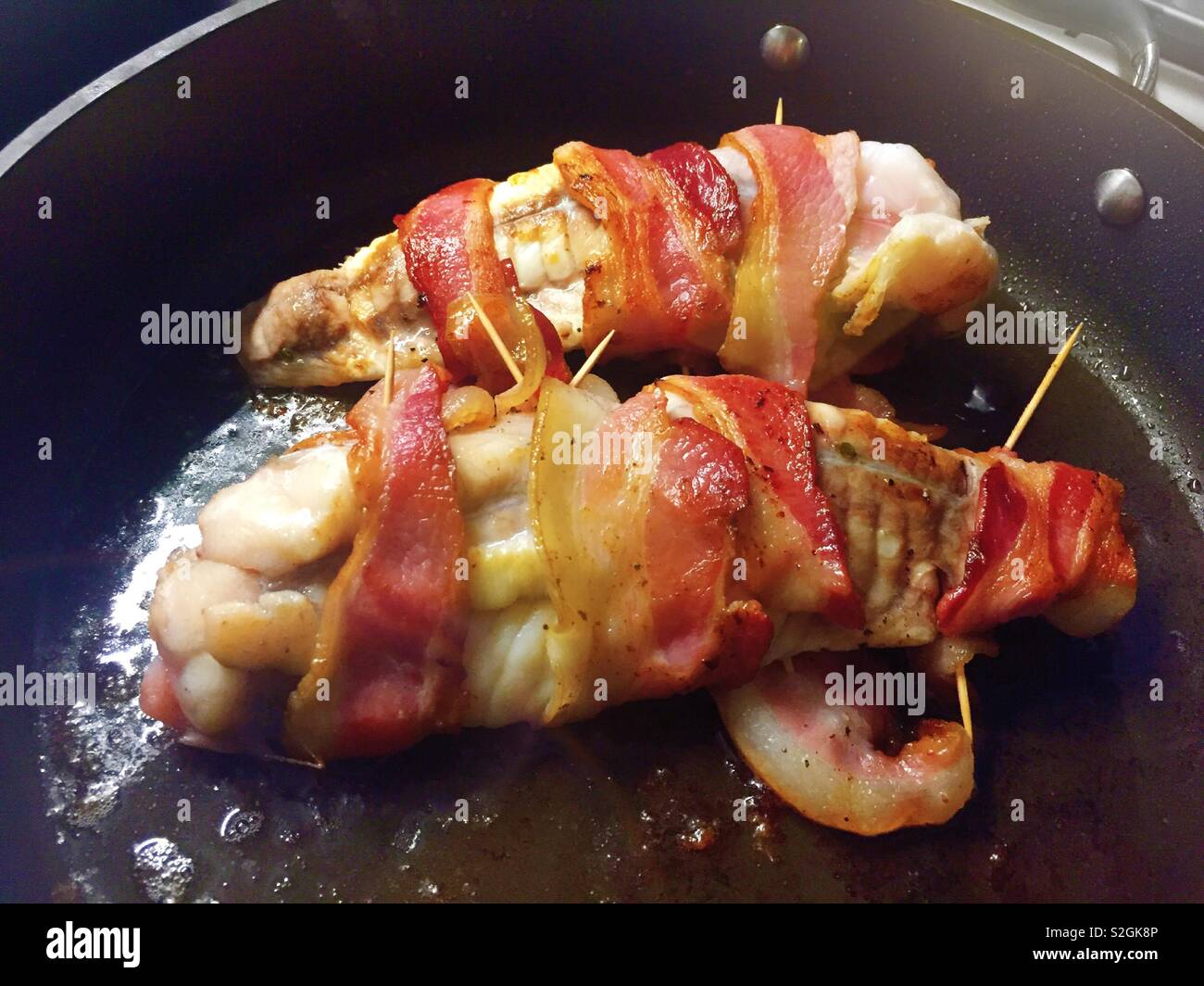 Monk fish fillet wrapped in bacon sautéing in a skillet, USA Stock Photo