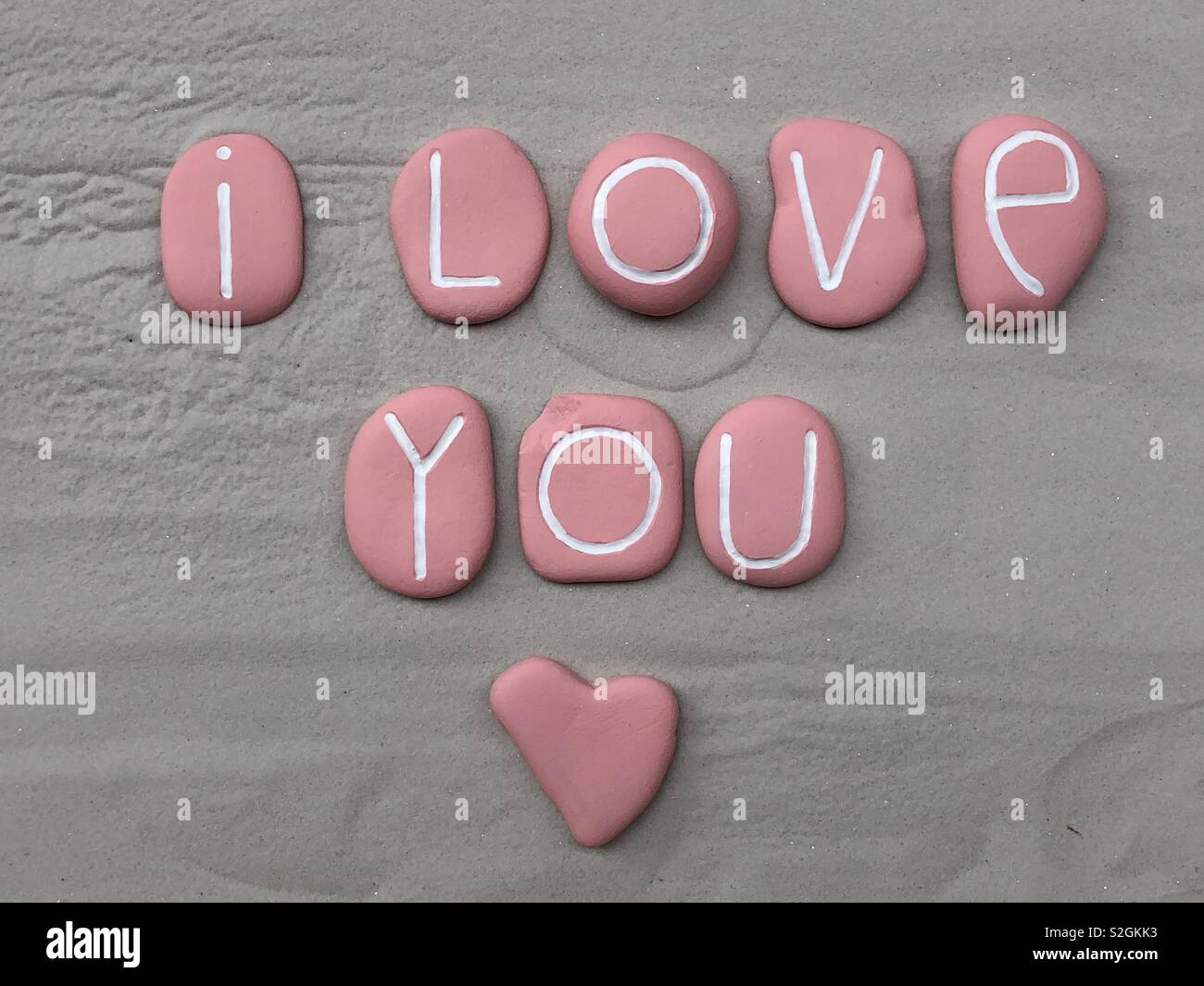 I love you with all my heart, conceptual composition with pink colored stones over white sand Stock Photo