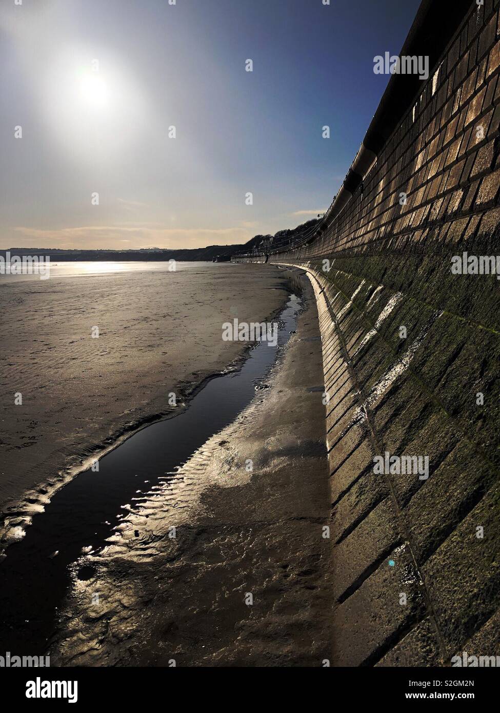 Low winter sun shining on a beach and sea wall - Smartphone Captured Stock Image