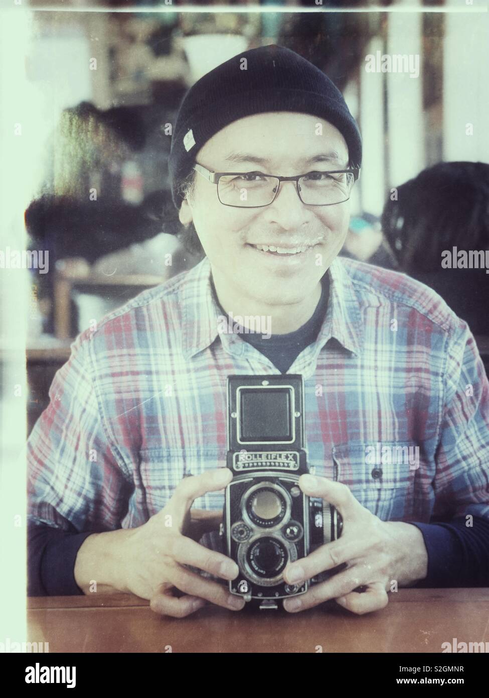 Happy middle aged Asian man holding vintage film Rolleiflex camera - Smartphone Captured Stock Image