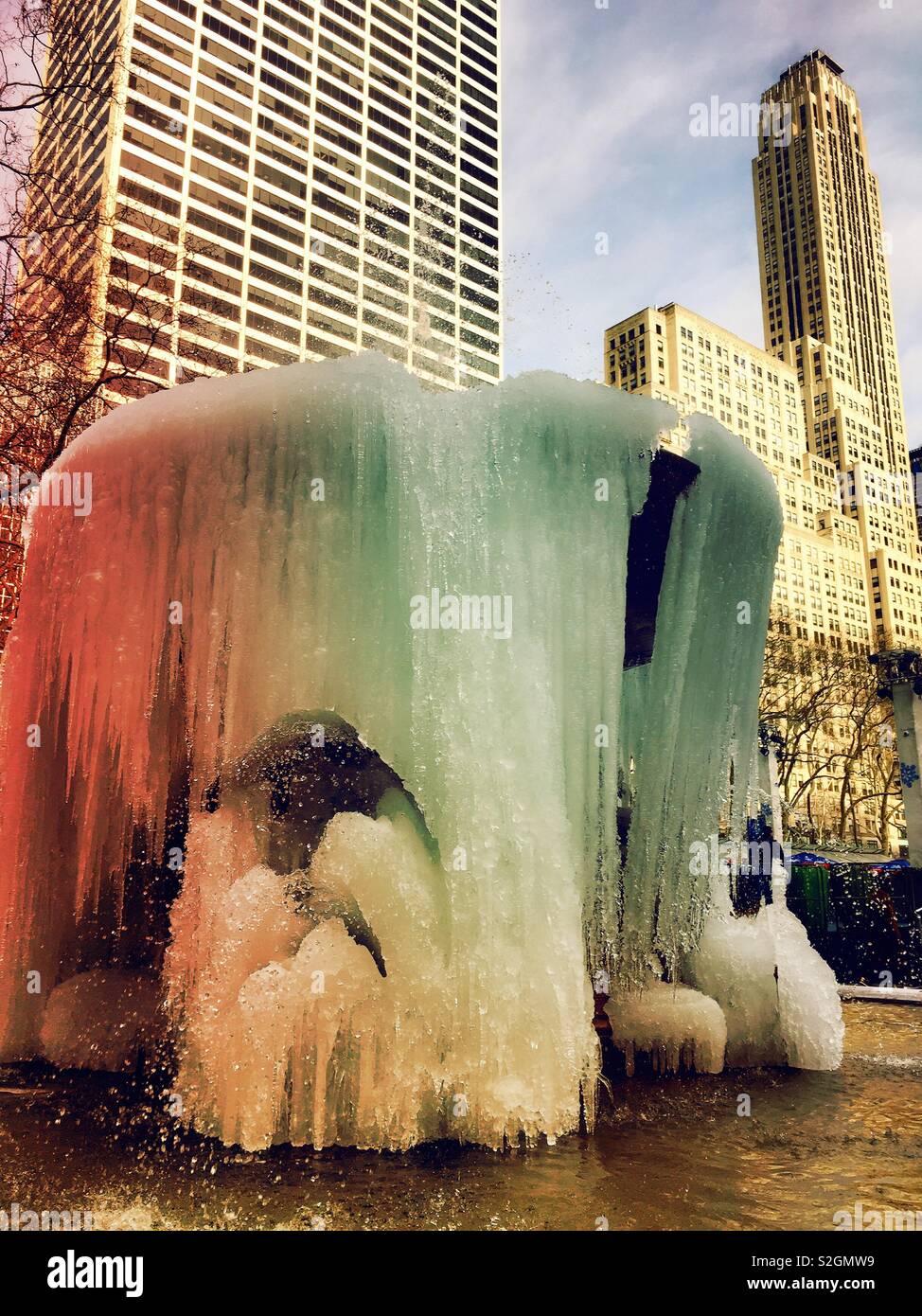 Icicles hanging from the Josephine Shaw Lowell Memorial fountain with midtown Manhattan skyscrapers in the background, Bryant Park, NYC, USA - Smartphone Captured Stock Image